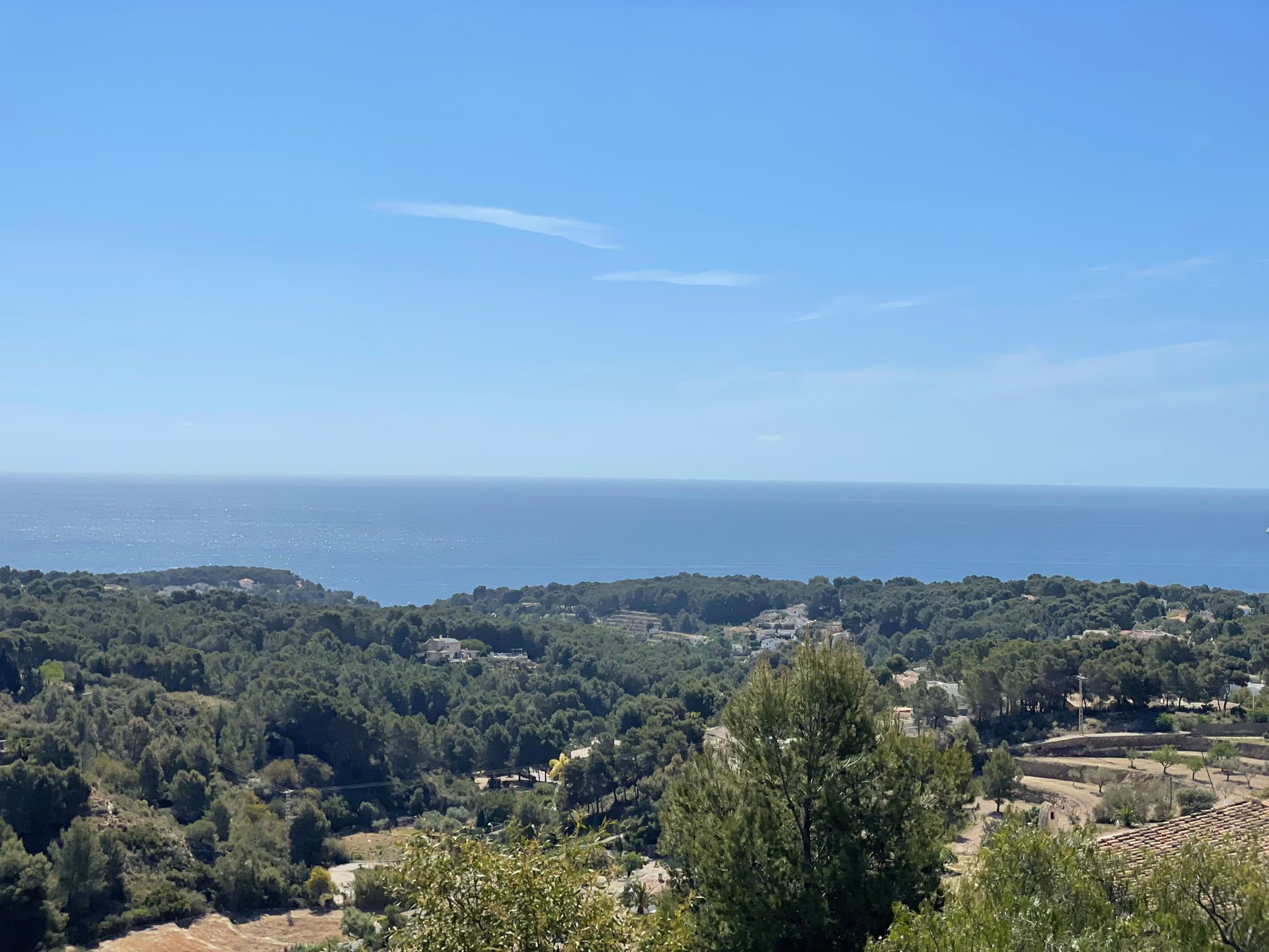Panoramablick auf das Mittelmeer vom Grundstück aus, über einen Pinienwald und die Küste von Benissa unter klarem blauem Himmel.