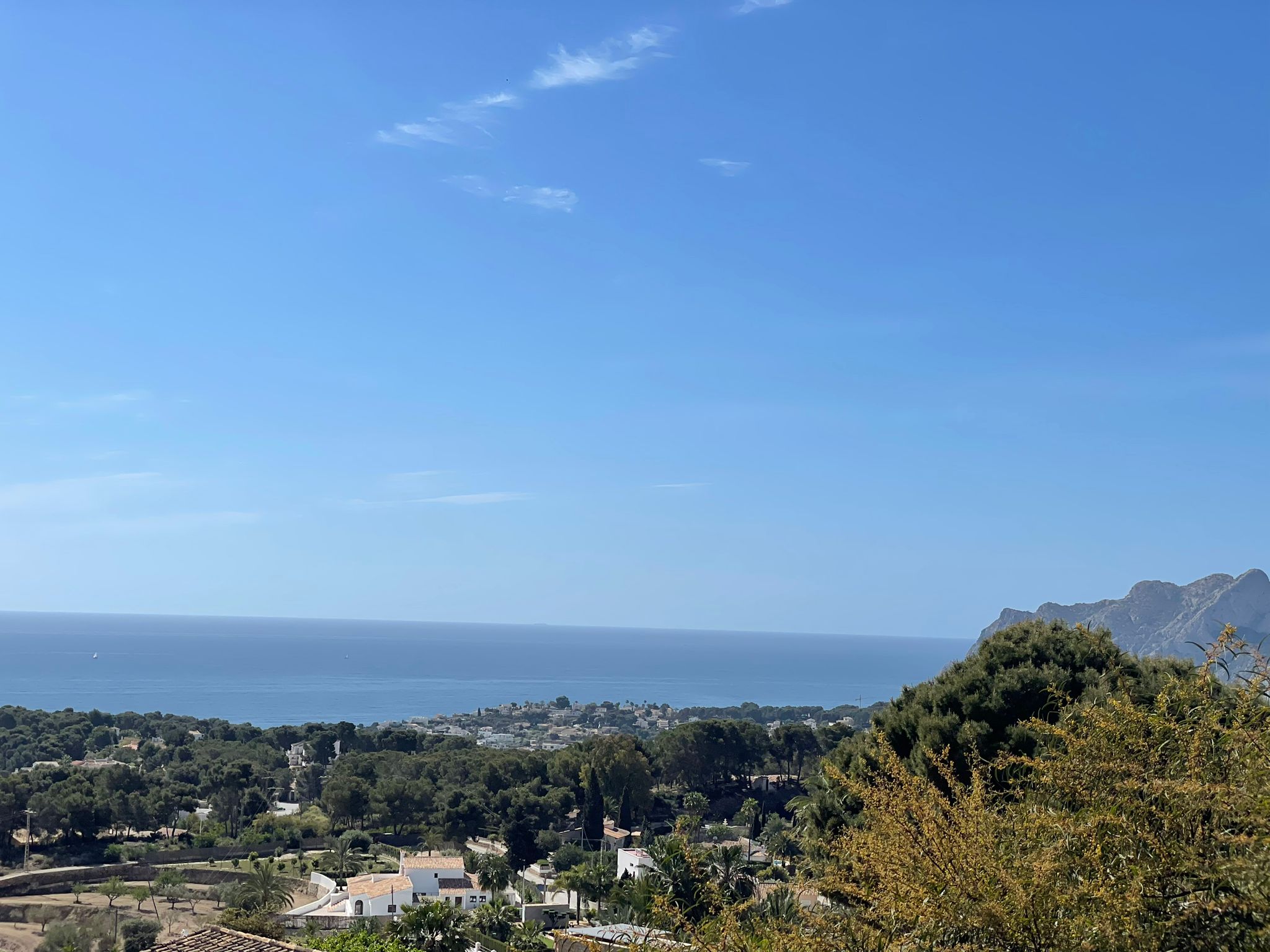 Panoramablick vom Anwesen auf die Küste von Benissa mit üppiger mediterraner Vegetation und dem Meer unter klarem blauem Himmel.