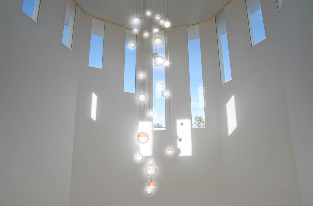Doppelte Deckenhöhe mit einem modernen Kronleuchter aus Glaskugeln und schmalen vertikalen Fenstern, die für viel natürliches Licht im Eingangsbereich sorgen.
