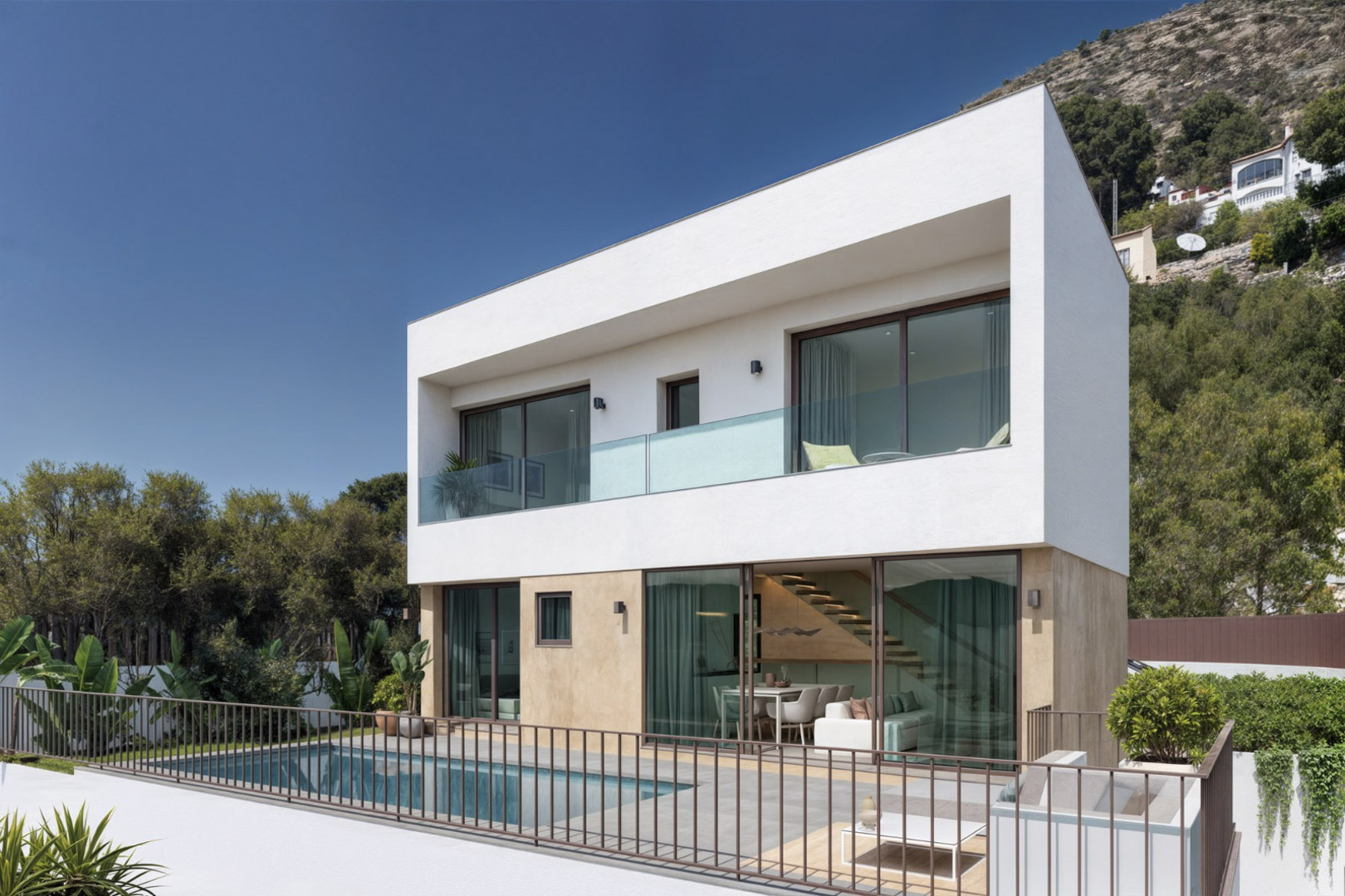 Moderne zweistöckige Villa mit privatem Pool, Steinterrasse und großen Glasfronten, die den Blick auf den Wohnbereich und die elegante Innentreppe freigeben.