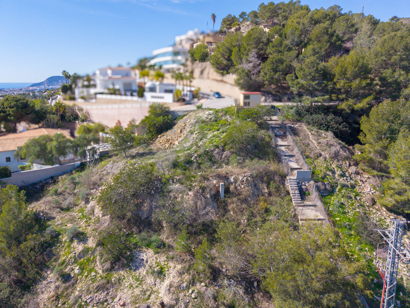 Erhöhte Ansicht des steilen Grundstücks in Benissa mit angelegtem Treppenaufgang und Panoramablick auf die Mittelmeerküste.