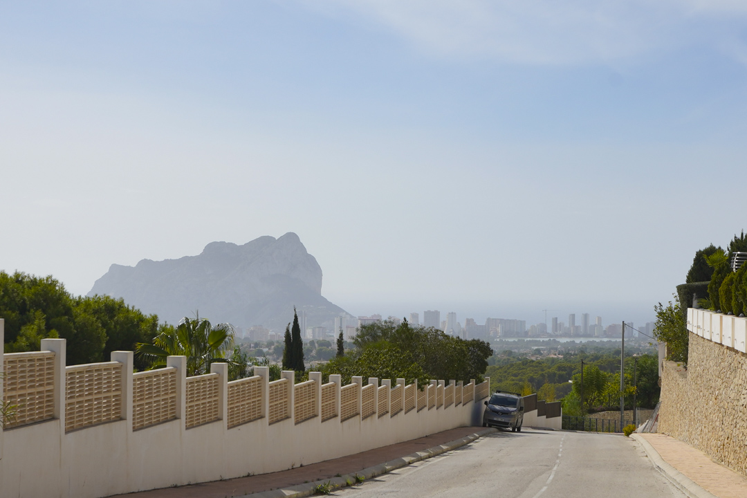 Panoramablick von der Zufahrtsstraße auf den Peñón de Ifach und die Skyline von Calpe, mit dem Mittelmeer im Hintergrund.
