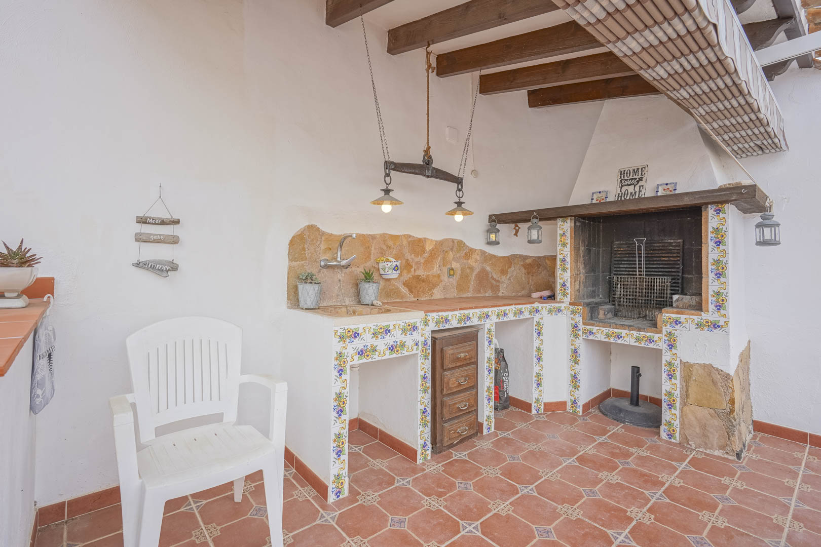 Außenbereich mit Grill, Steinarbeitsplatte und dekorativen Fliesen in einer Villa im spanischen Stil.