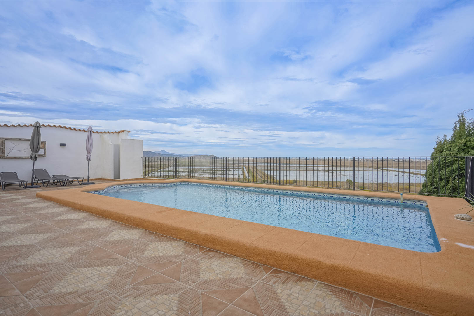 Blick auf den Pool mit ockerfarbenem Rand und Terrakottafliesen mit Blick auf das Naturschutzgebiet.