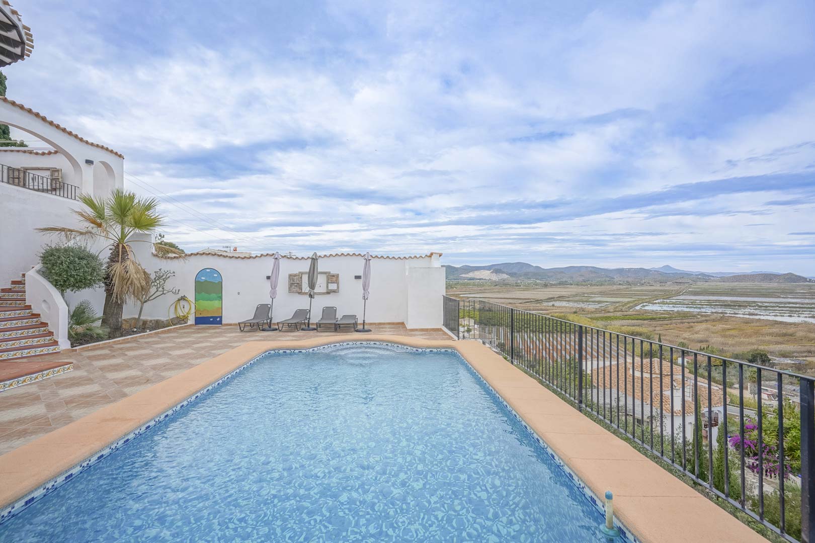 Blick auf den privaten Pool mit blauen Fliesen und Terrasse mit Panoramablick auf das Naturschutzgebiet.