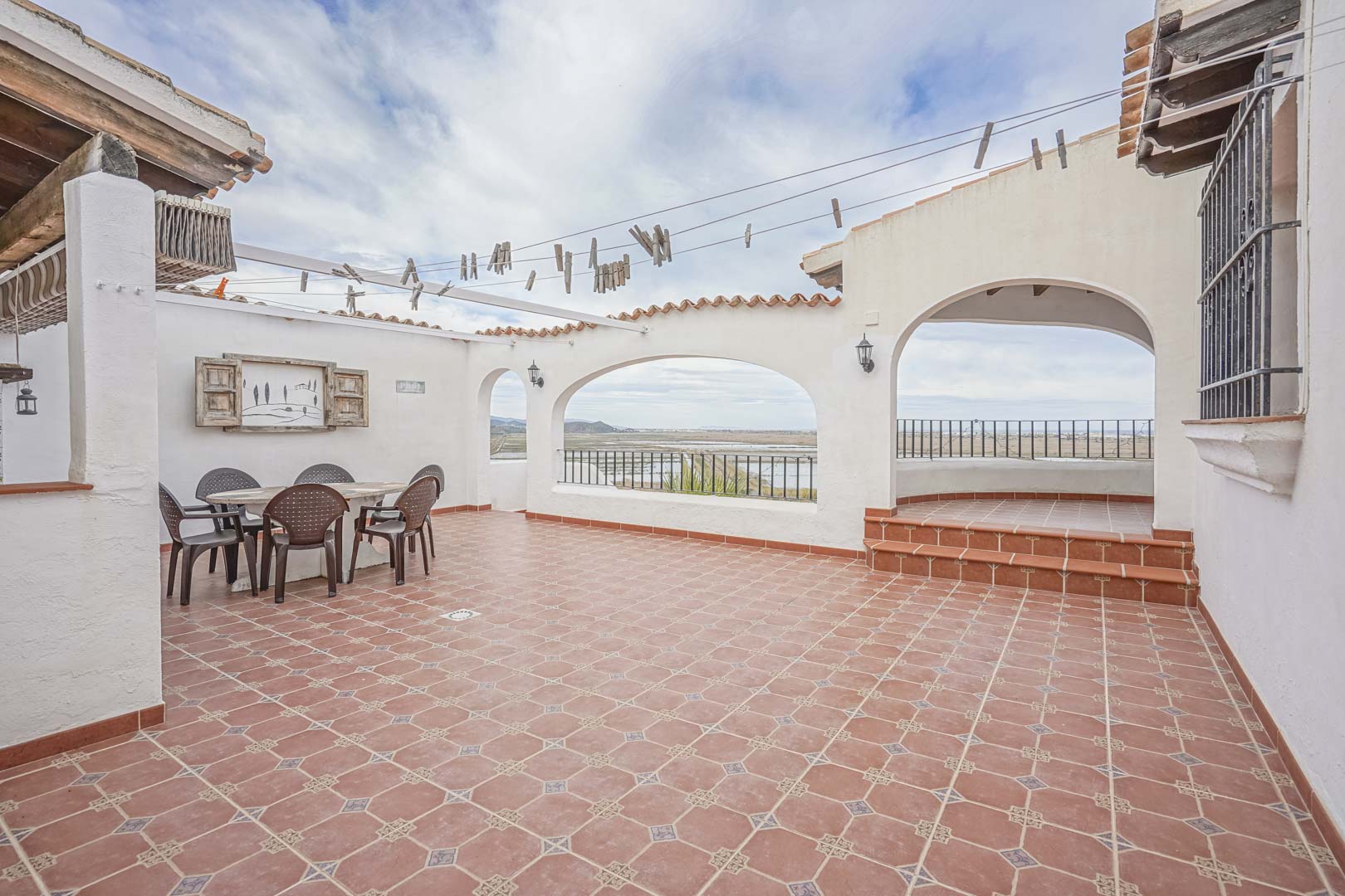 Geräumige, geflieste Terrasse mit Blick auf das Naturschutzgebiet, ideal für Mahlzeiten im Freien.
