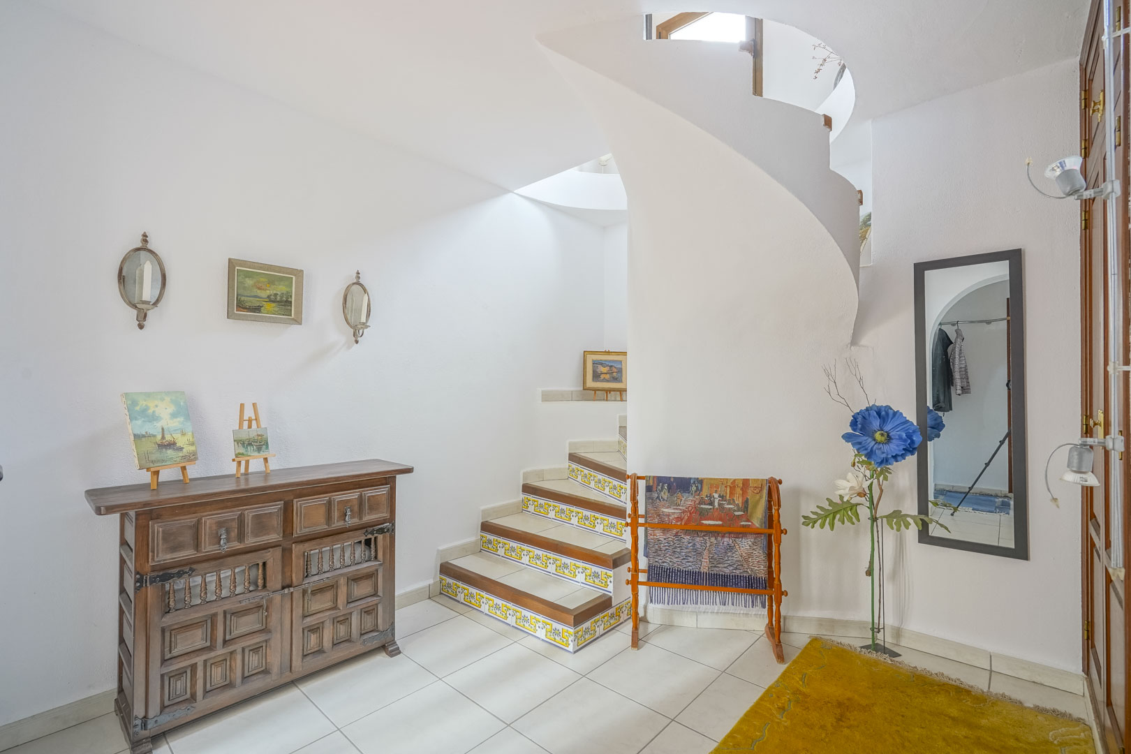 Helles Foyer mit Wendeltreppe und rustikalen Details, wie dem hölzernen Sideboard.