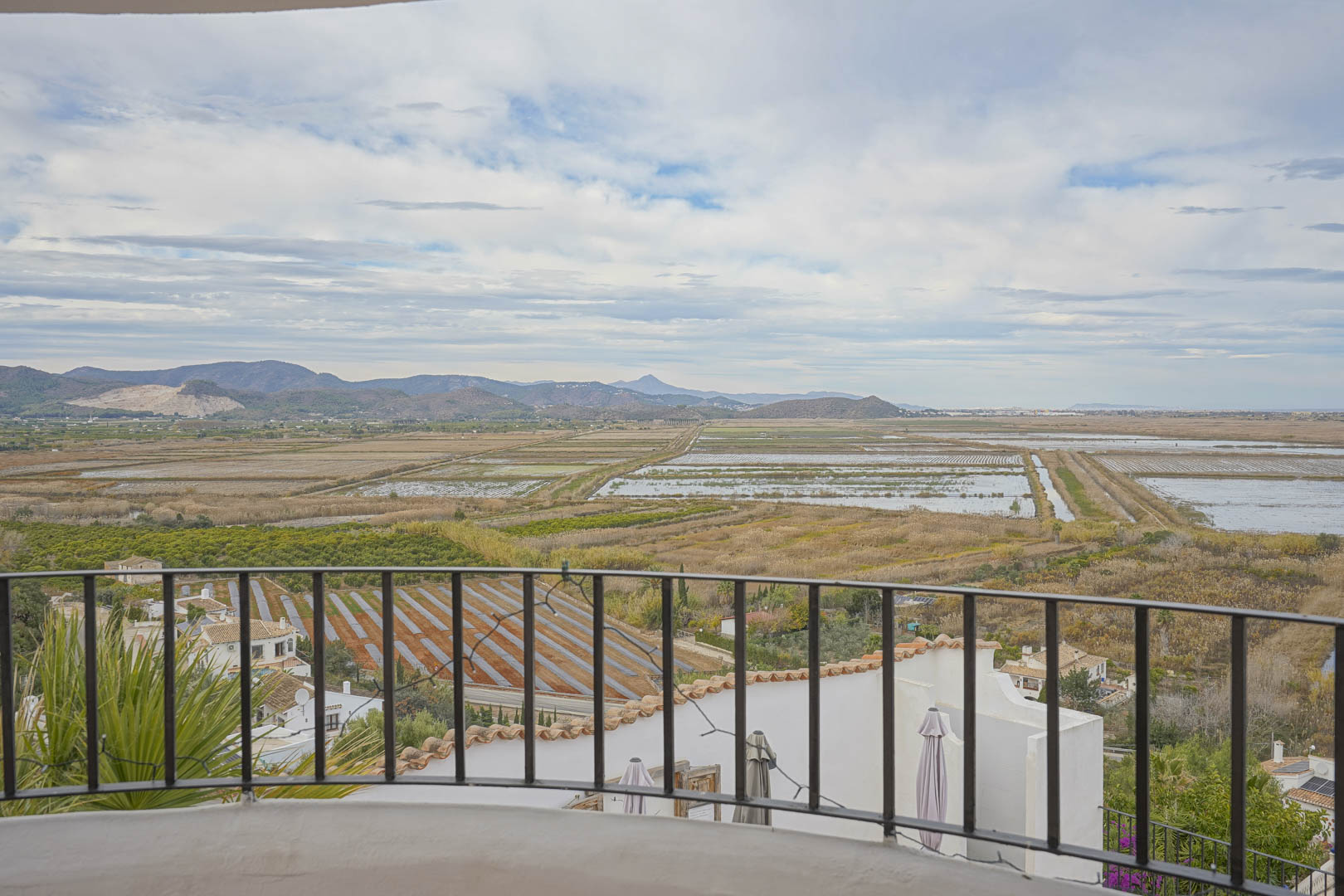 Panoramablick von der Terrasse mit schmiedeeisernem Geländer über die Reisfelder und die Berglandschaft.