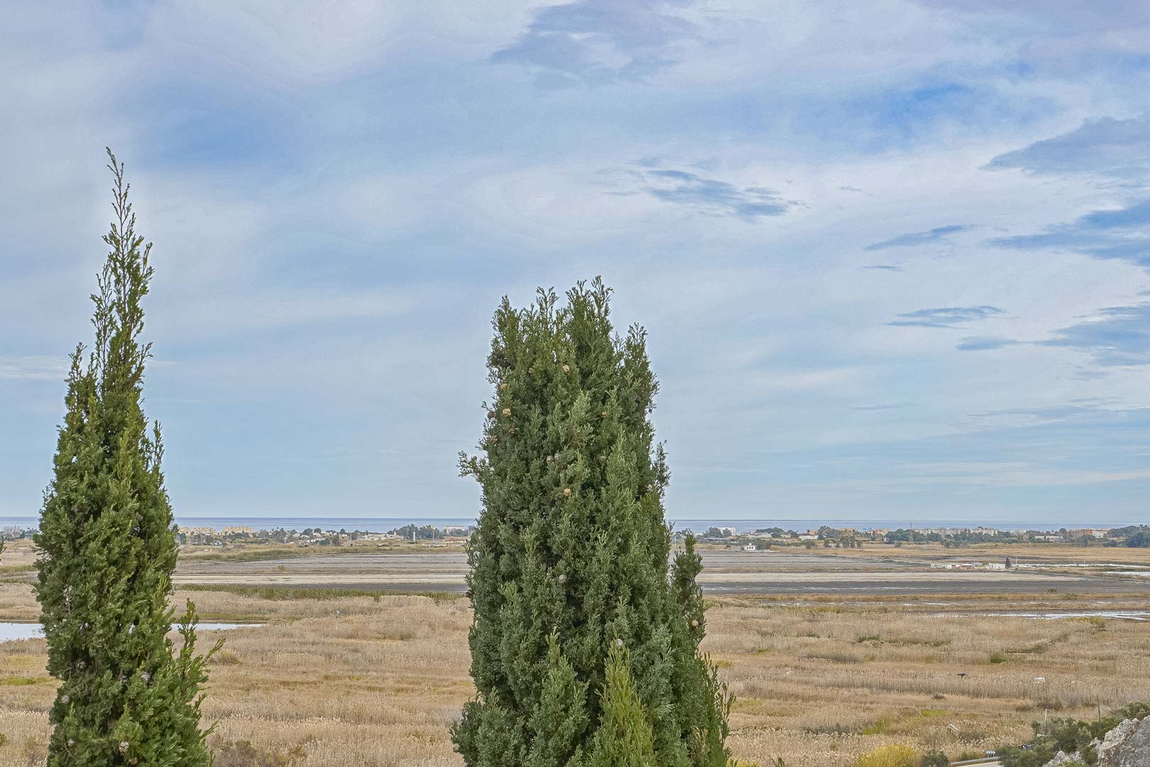 Panoramablick von Monte Pego mit Zypressen im Vordergrund und der Küstenlinie in der Ferne.
