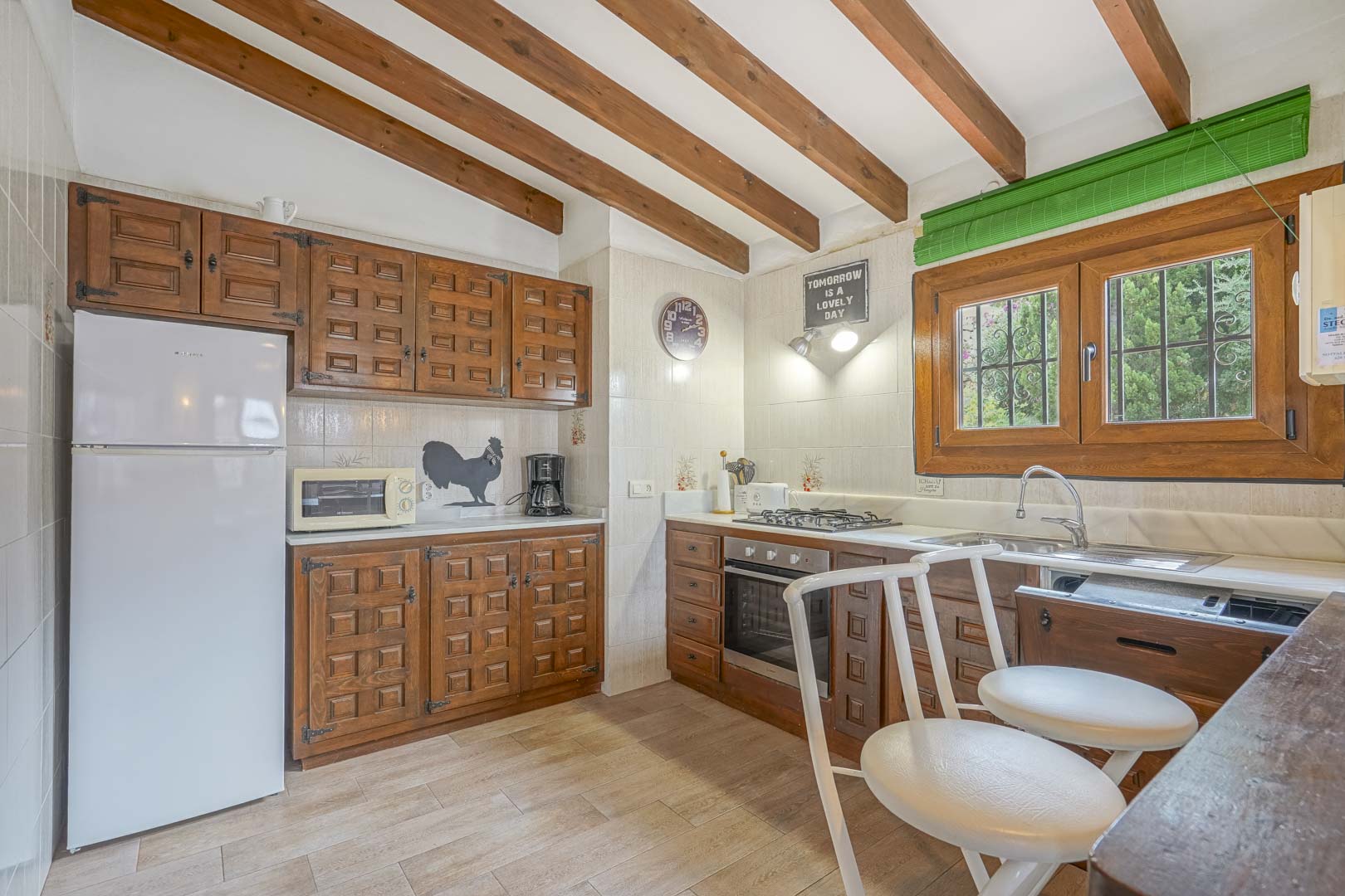 Rustikale Küche mit Holzbalkendecke, geschnitzten Holzschränken und modernen Geräten.