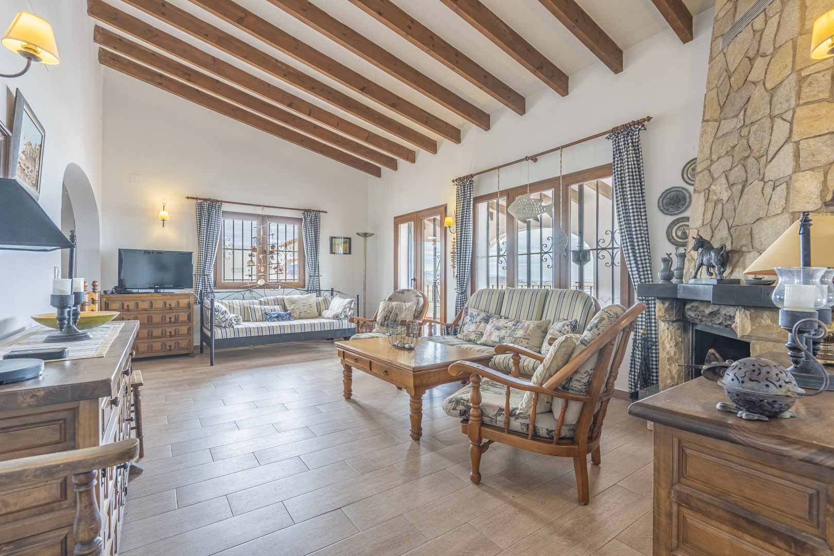 Wohnzimmer mit Holzbalken, Steinkamin und rustikalen Möbeln.