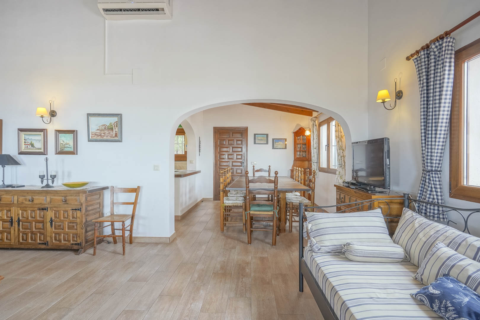 Wohnzimmer mit Keramikböden, gewölbten Öffnungen zum Essbereich und rustikalen Holzmöbeln.