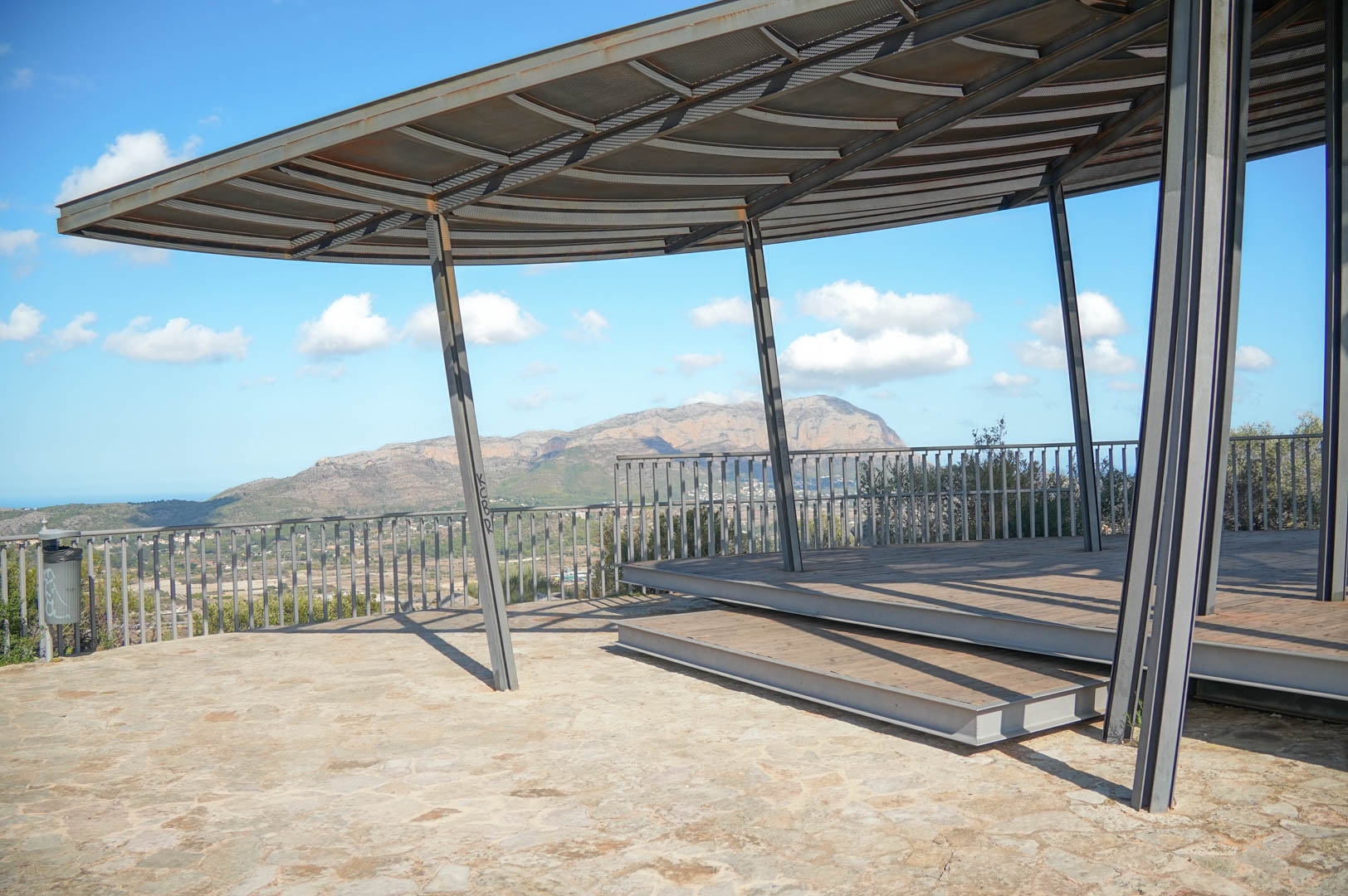 Aussichtspunkt im Freien mit moderner Stahlkonstruktion und Holzdeck, der einen Panoramablick auf die Berge und das Tal bietet.