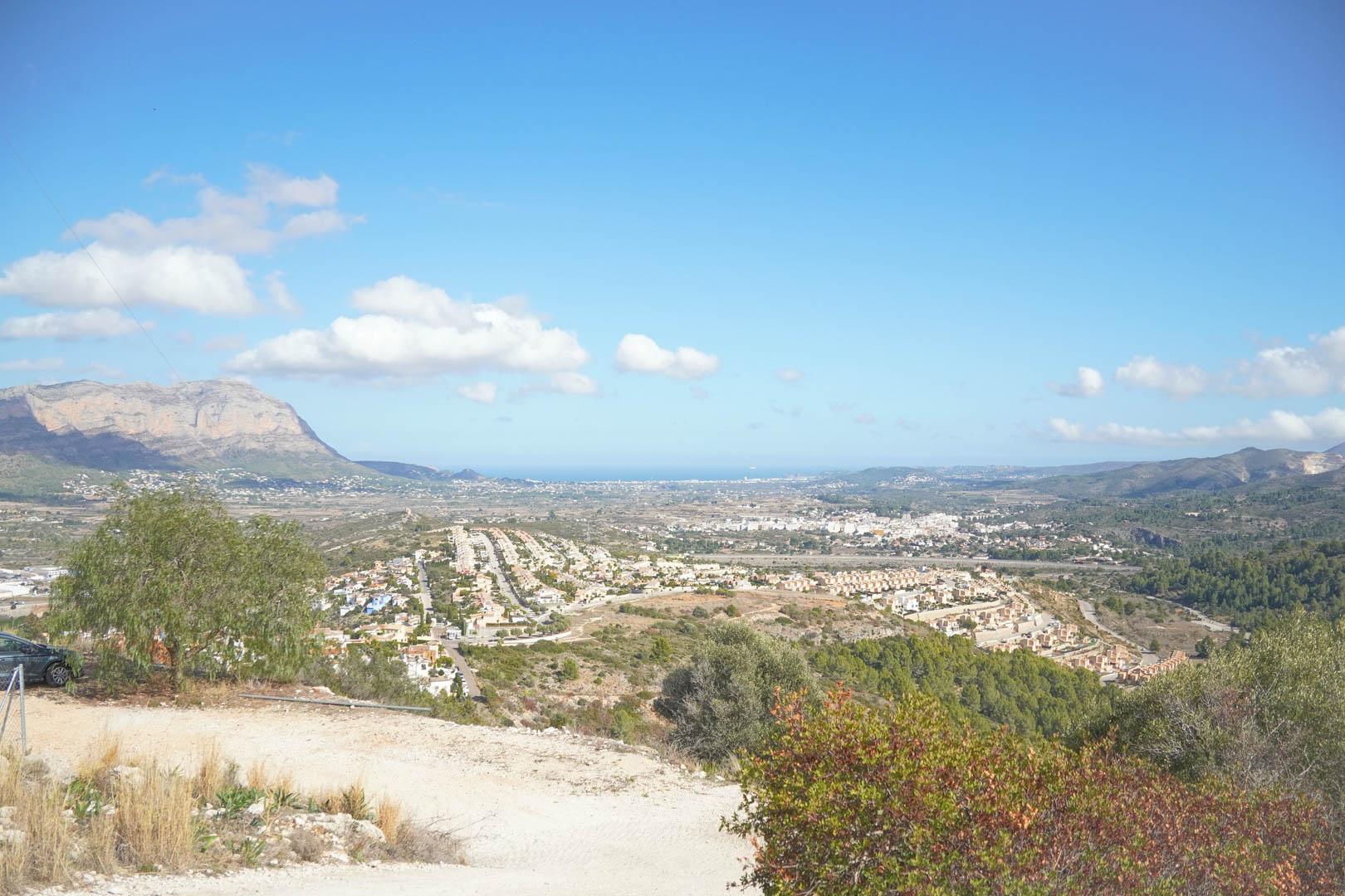Erhöhter Panoramablick über das Tal von Pedreguer mit dem Montgó-Massiv und dem Mittelmeer am Horizont unter klarem Himmel.