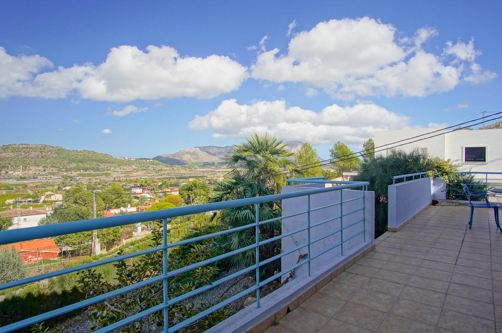 Obere Terrasse mit Fliesenboden und blauem Geländer, die einen weiten Panoramablick über das Pedreguer-Tal und die umliegenden Berge bietet.