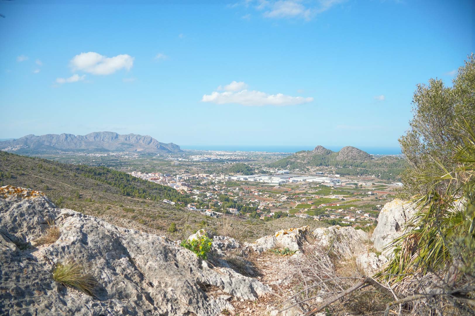 Panoramablick vom Anwesen über das Pedreguer-Tal, die umliegenden Berge und das Mittelmeer am Horizont unter klarem Himmel.
