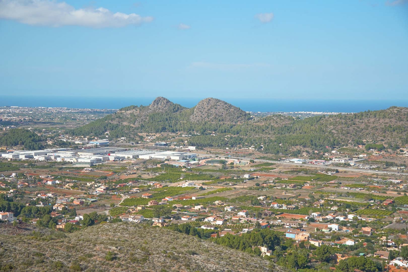 Panoramablick vom Anwesen über das Pedreguer-Tal mit den umliegenden Bergen und dem Mittelmeer am Horizont unter einem klaren blauen Himmel.
