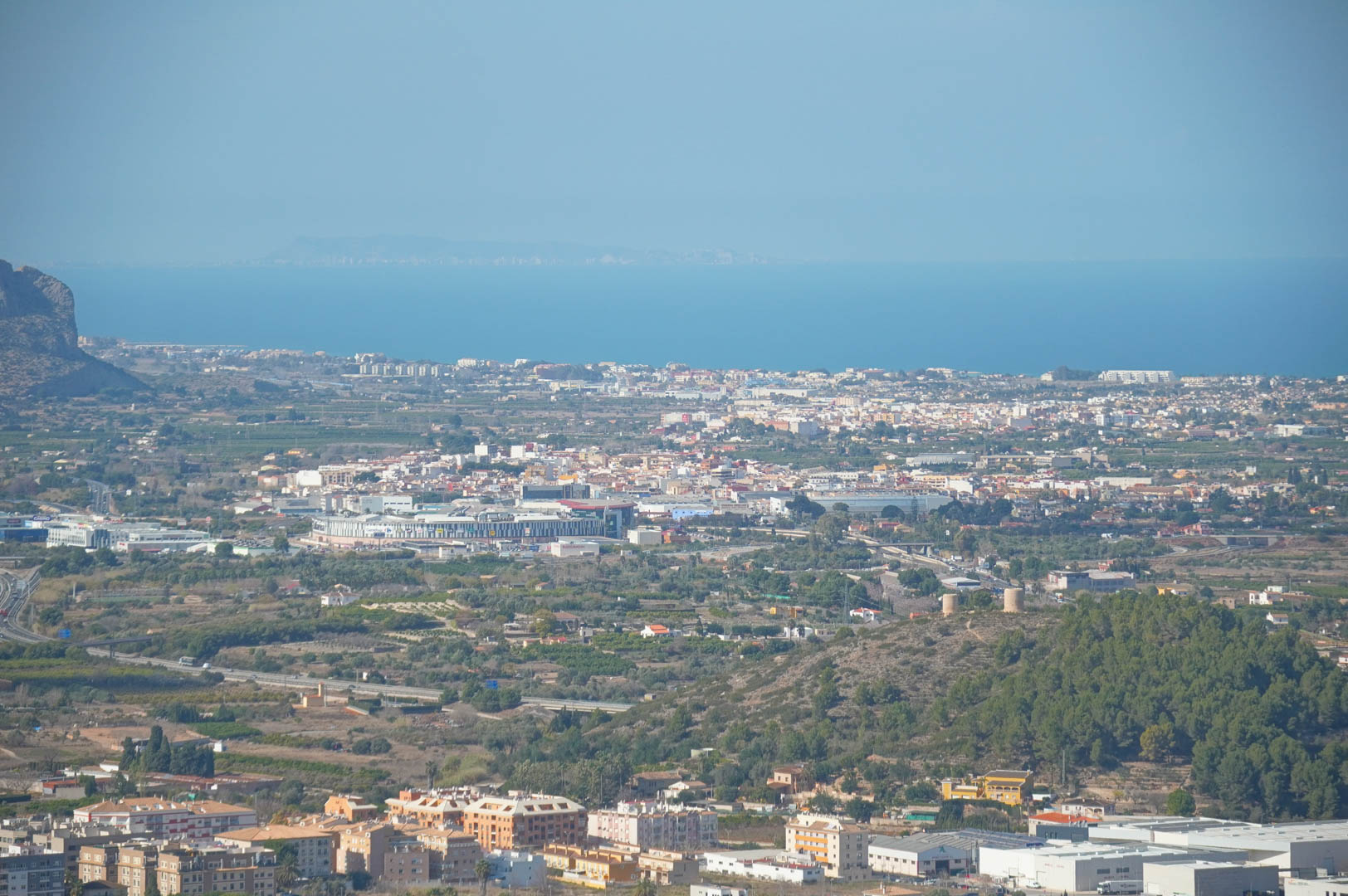 Panoramablick vom Anwesen über das Tal, Stadtgebiete und das Mittelmeer am Horizont unter klarem Himmel.