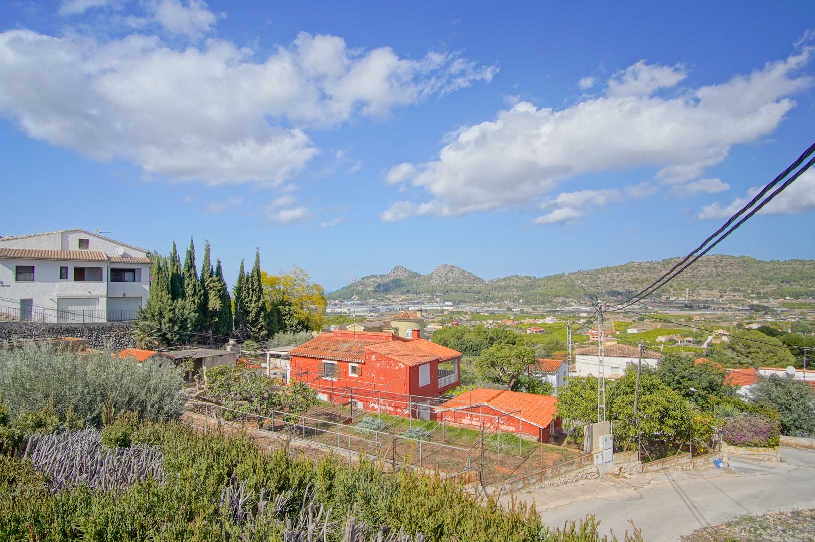 Panoramablick vom Anwesen über das Tal und die Berge von Pedreguer, mit mediterraner Vegetation und einer ruhigen Wohngegend unter klarem Himmel.