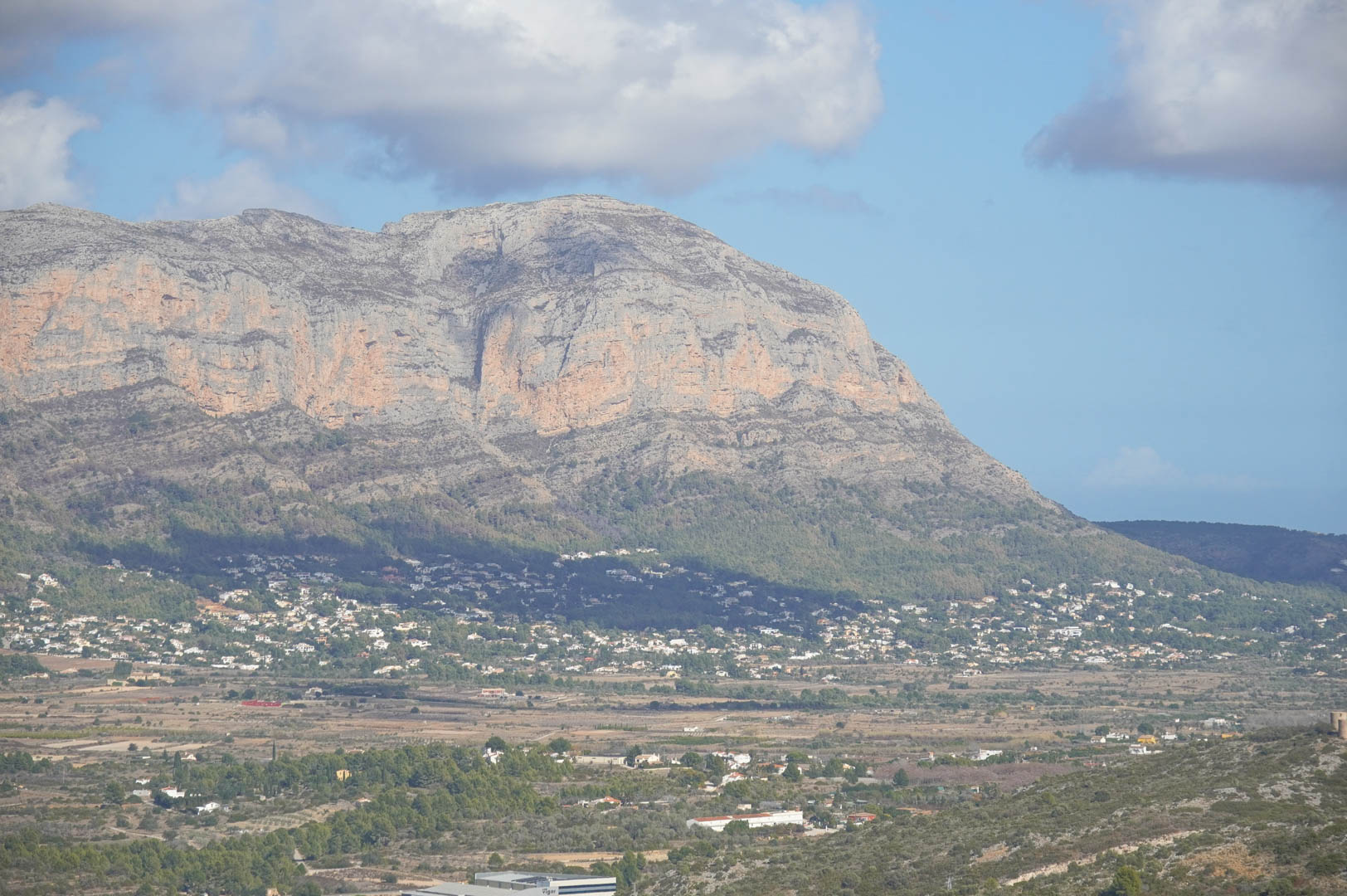 Panoramablick von dem Anwesen auf das Tal und das Kalksteingebirge, der die Einbettung der Wohngebiete in die mediterrane Landschaft unter klarem Himmel zeigt.