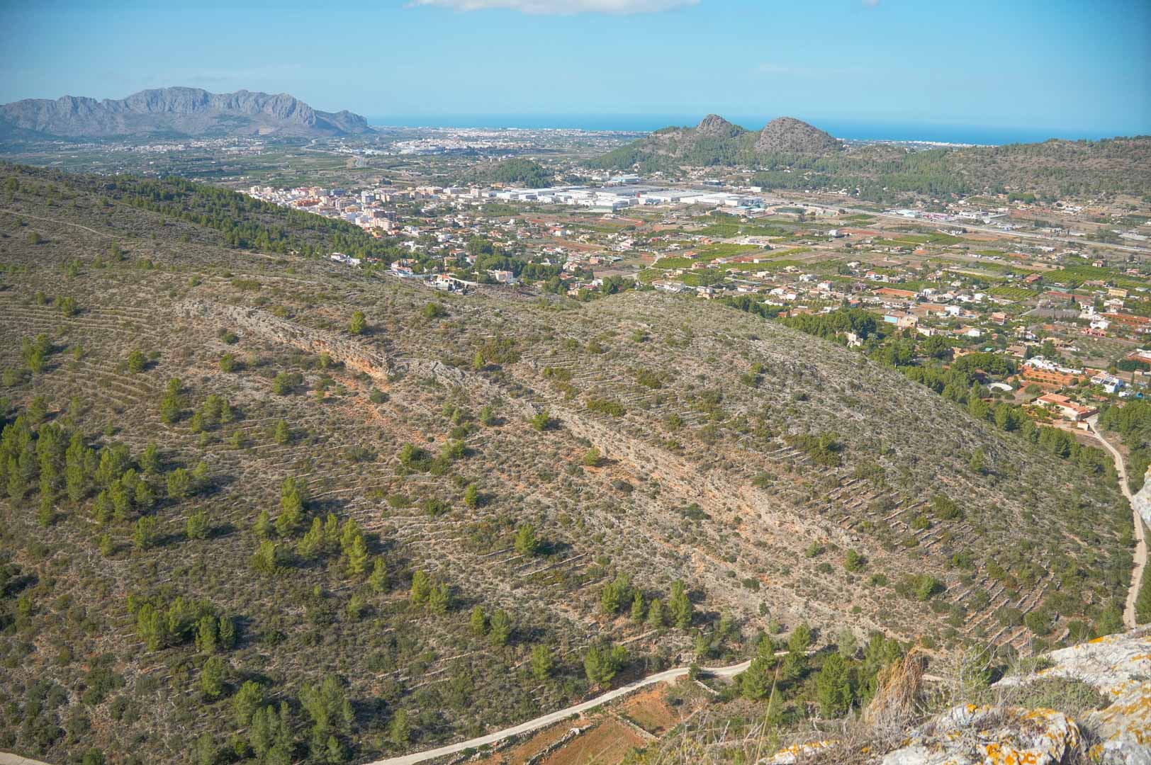 Panoramablick von der Anhöhe über das Tal von Pedreguer mit Blick auf die umliegenden Gebirgsketten und das Mittelmeer am fernen Horizont.
