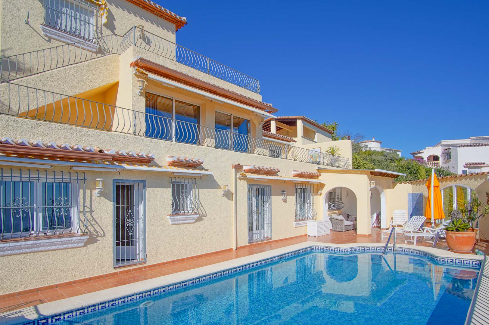 Außenansicht der Villa mit privatem Pool, Terrakotta-Terrassen und dreistöckiger Fassade. Mit bogenförmigem Chill-out-Bereich und schmiedeeisernen Geländern.