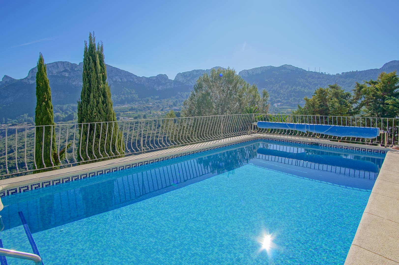 Außenpool mit blauen Mosaikfliesen, Metallgeländer und Panoramablick auf die umliegende Berglandschaft und das Tal von Monte Pego.