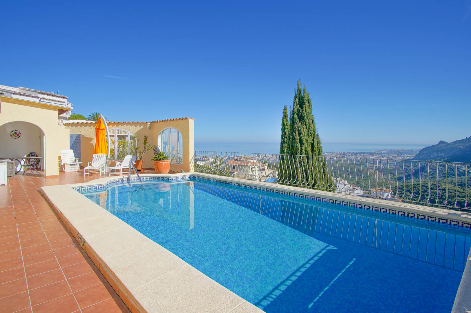 Rechteckiger Pool mit blauen Mosaikfliesen und Terrakotta-Terrasse mit Panoramablick auf das Mittelmeer und die umliegende Berglandschaft von Monte Pego.