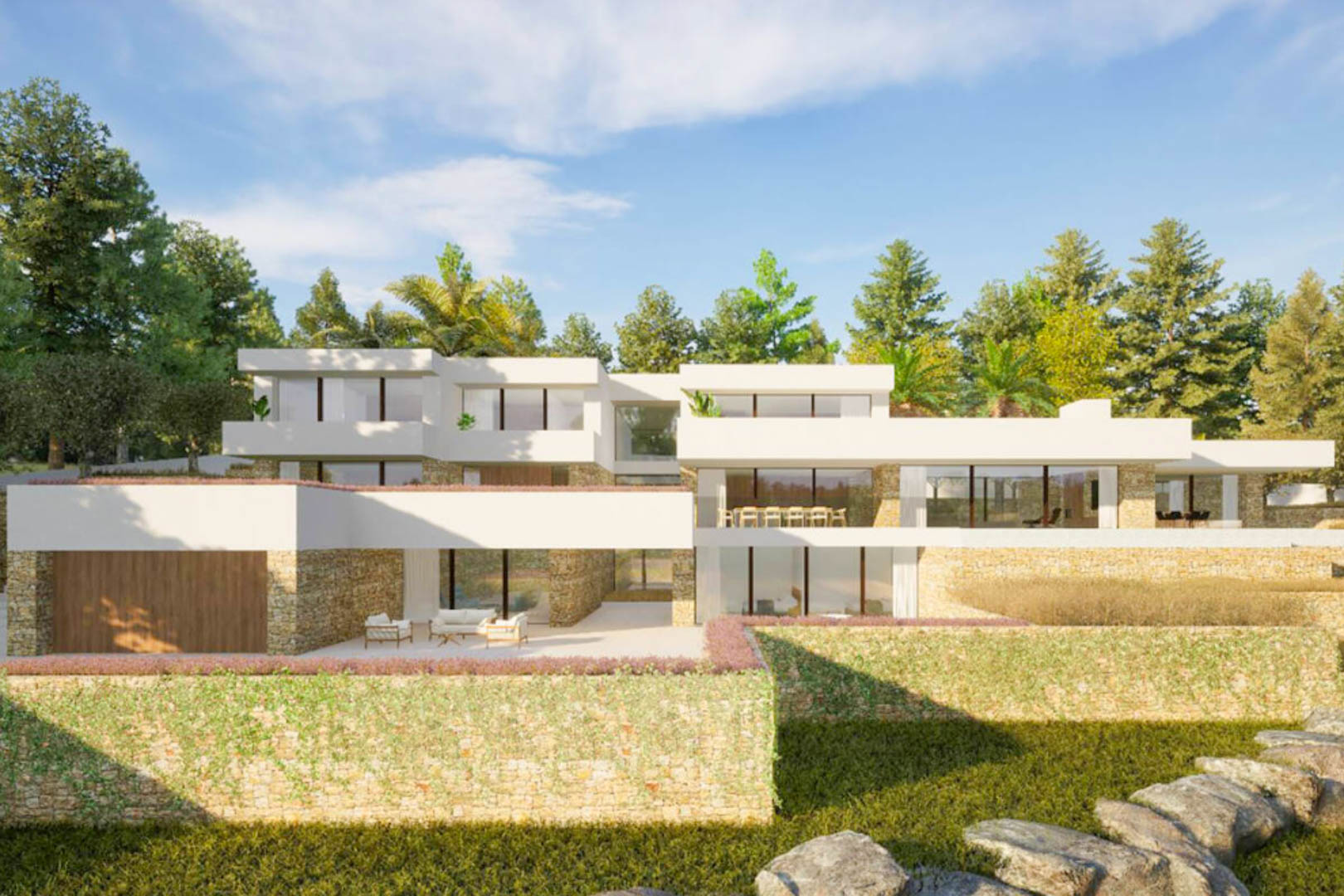 Außenfassade der Villa im ibizenkischen Stil mit Natursteinmauern, großen Glasfronten und Terrassen, die harmonisch in die mediterrane Gartenlandschaft eingebettet sind.