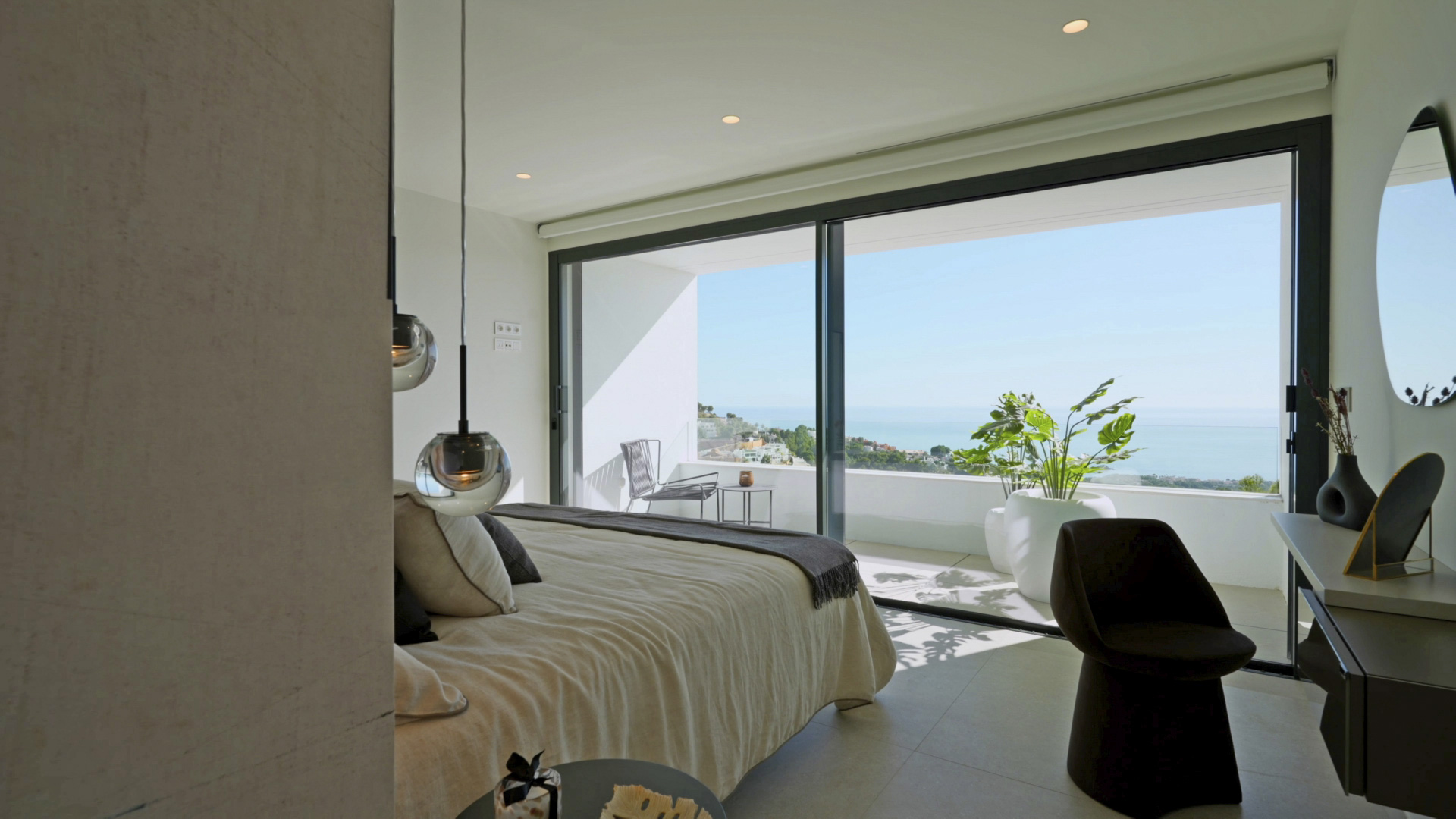 Hauptschlafzimmer mit bodentiefen Glasschiebetüren, privater Terrasse mit Meerblick und modernen Pendelleuchten. Minimalistisches Design mit Einbaustrahlern.