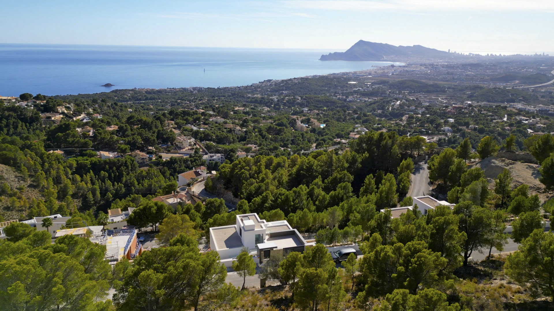 Luftaufnahme der modernen Villa in Sierra de Altea, eingebettet in einen Pinienwald mit Panoramablick auf das Mittelmeer und die Küstenlinie.