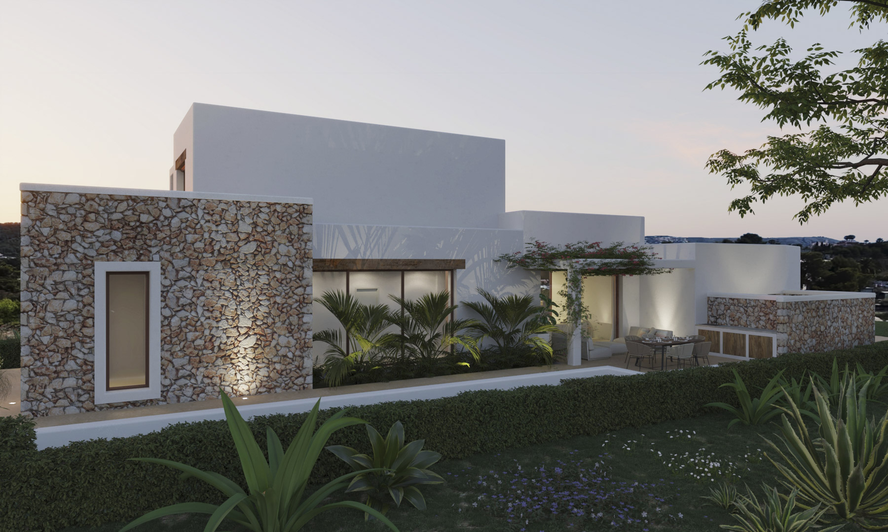 Außenansicht im ibizenkischen Stil mit Natursteinwänden, weißen Baukörpern und einer Essterrasse inmitten mediterraner Bepflanzung bei Abenddämmerung.