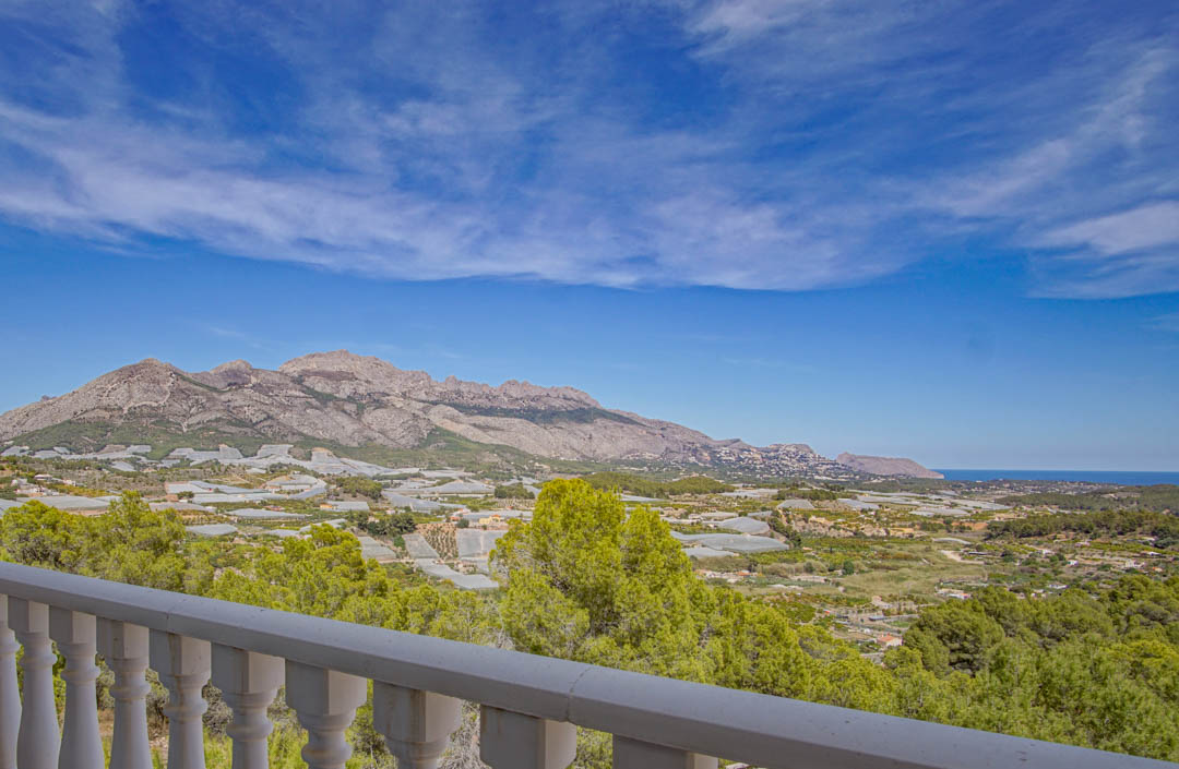 Panoramablick von der Terrasse mit weißer Balustrade auf das Tal, die umliegenden Berge und den Horizont des Mittelmeers.