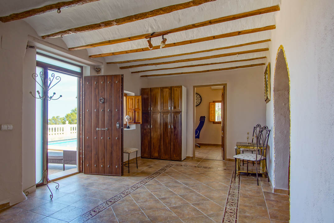 Rustikaler Eingangsbereich mit sichtbaren Holzbalkendecken, verzierten Fliesenböden und einer massiven Holztür, die direkt zur Poolterrasse führt.