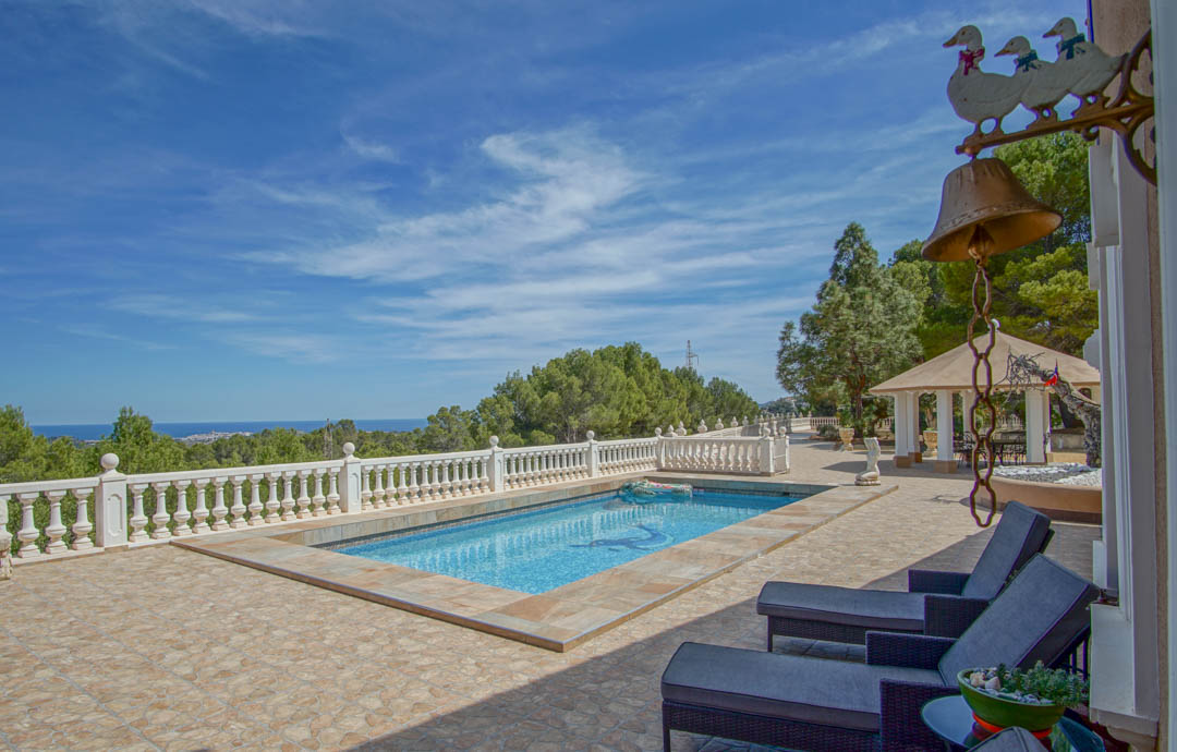 Terrasse mit Mosaikpool und weißer Balustrade, die einen weiten Blick auf die Mittelmeerküste und die umliegenden Pinienwälder bietet.