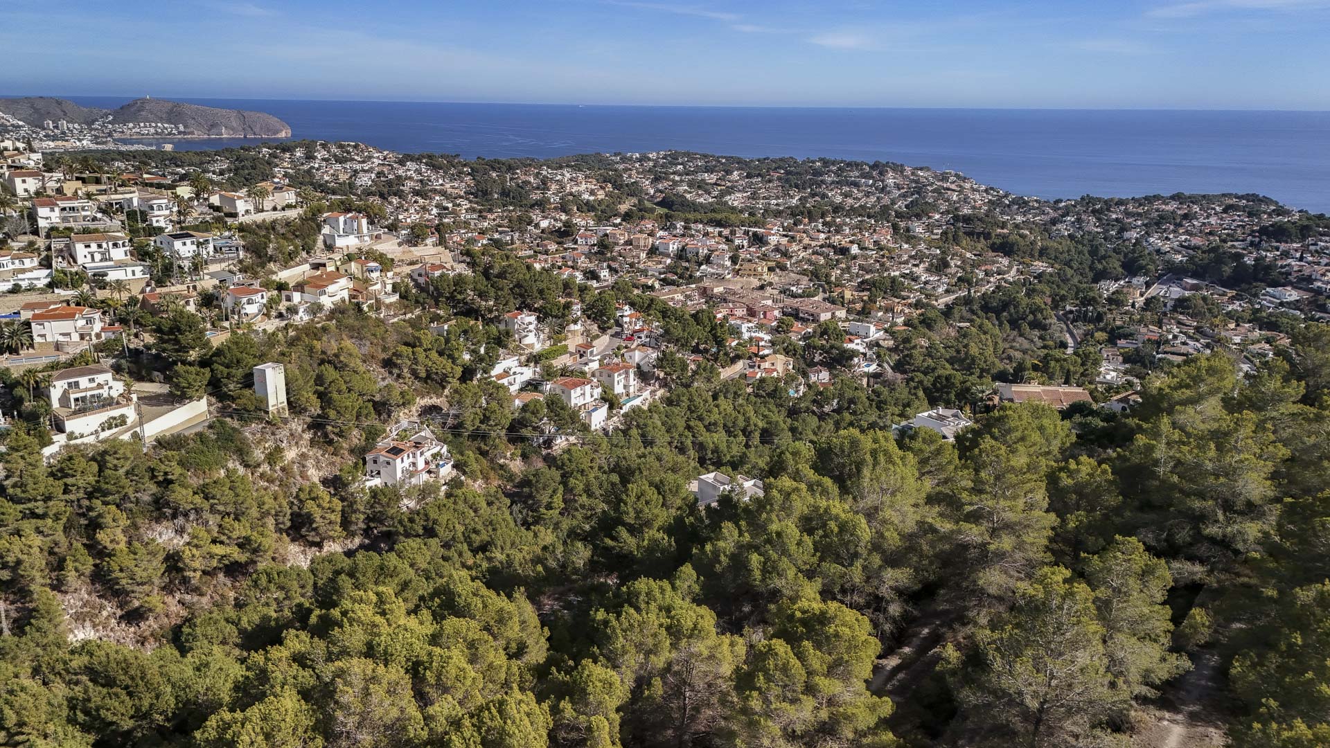 Luftaufnahme der Wohngegend in Benissa, eingebettet in dichte Pinienwälder mit weitem Panoramablick auf das Mittelmeer und die Küstenlinie.