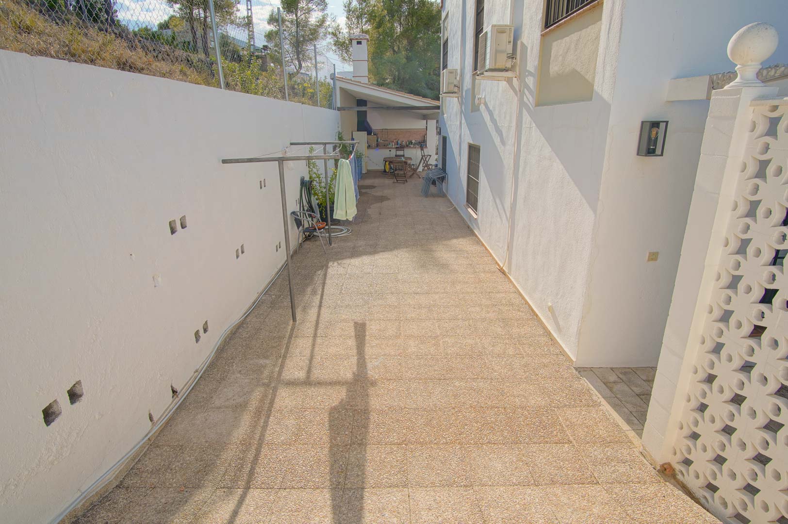 Gepflasterter Seitenweg mit Wäscheständer, der zum überdachten Grillbereich und der Außenküche im hinteren Garten führt.