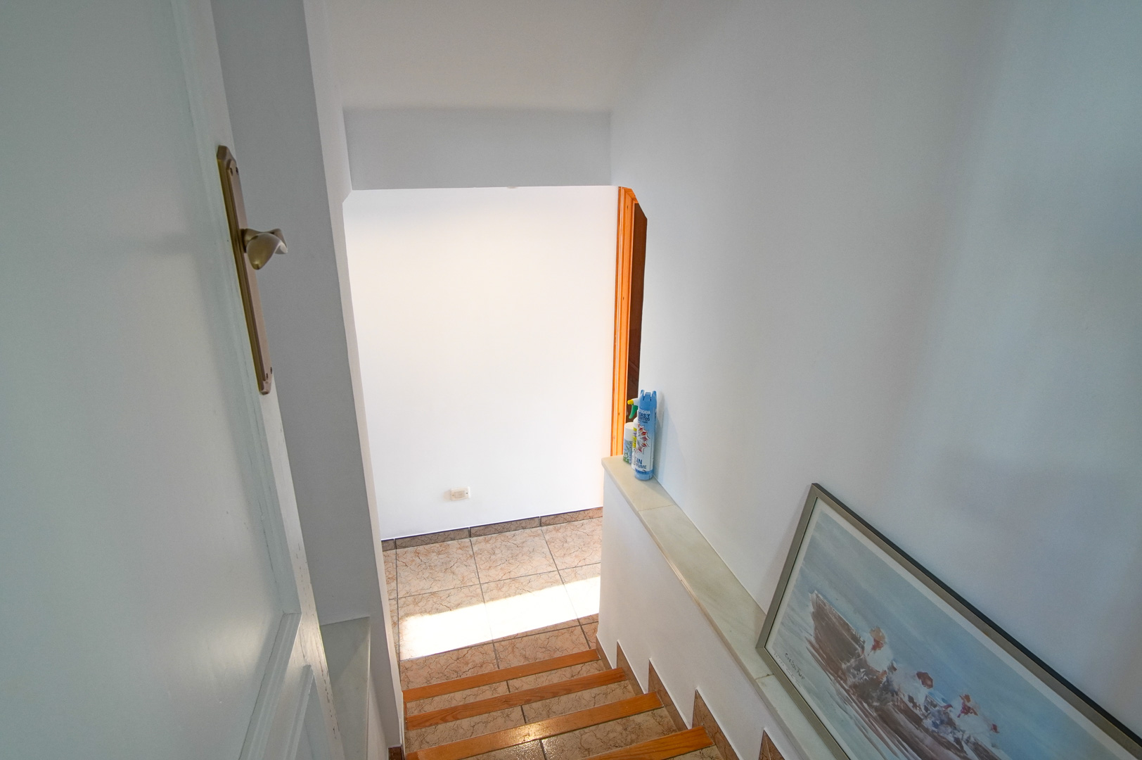 Innenliegende Treppe mit Holz- und Keramikelementen, die durch helle, weiße Wände und natürliches Licht eine freundliche Verbindung der Etagen schafft.