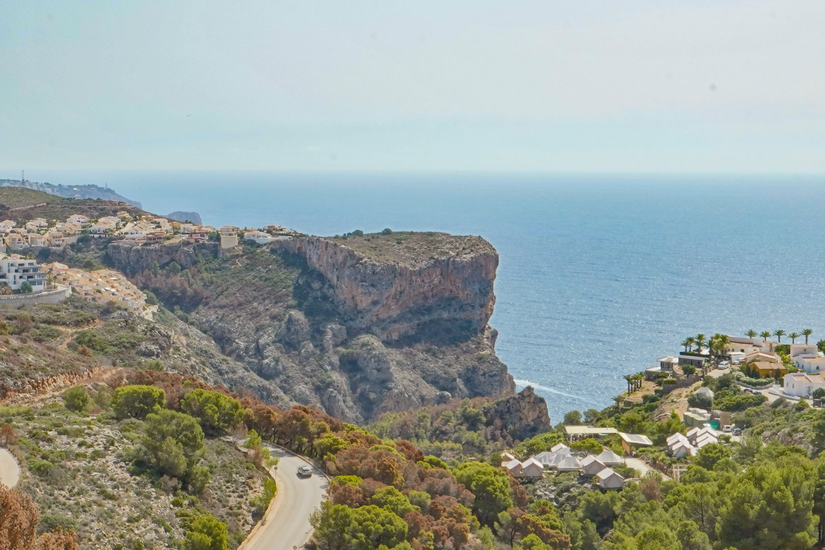 Panoramablick von Cumbre del Sol auf die Klippen und das Mittelmeer, mit der sich durch die Vegetation schlängelnden Küstenstraße.