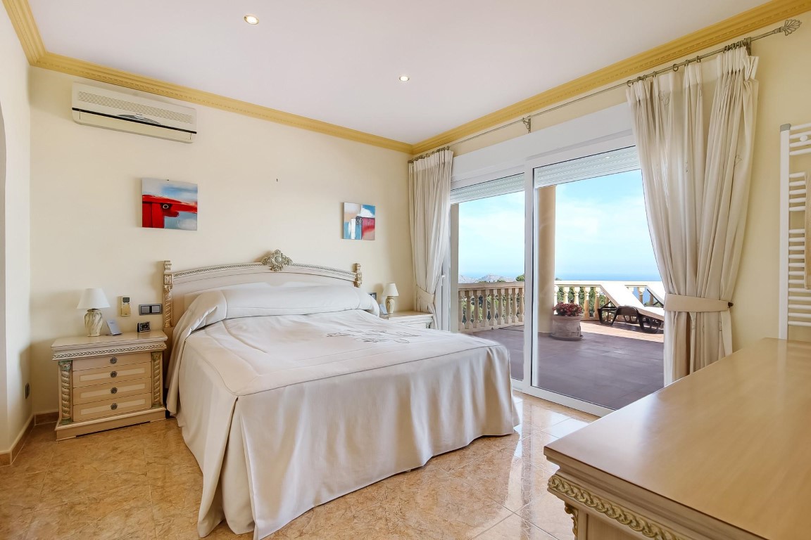 Hauptschlafzimmer mit Terrassenzugang, Fliesenboden, Klimaanlage und großen Schiebetüren mit weitem Blick auf das Mittelmeer.