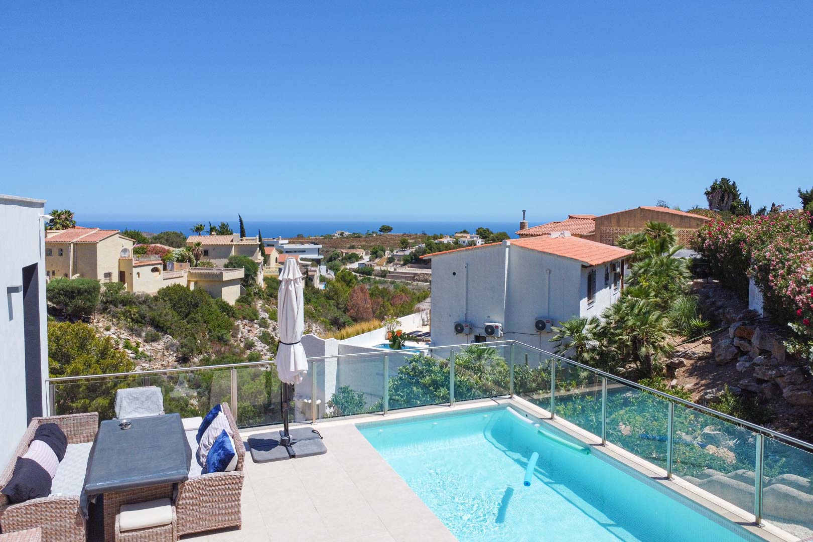 Außenterrasse mit Pool, Glasgeländer und Essbereich aus Korbgeflecht, mit Panoramablick auf das Mittelmeer in Cumbre del Sol.