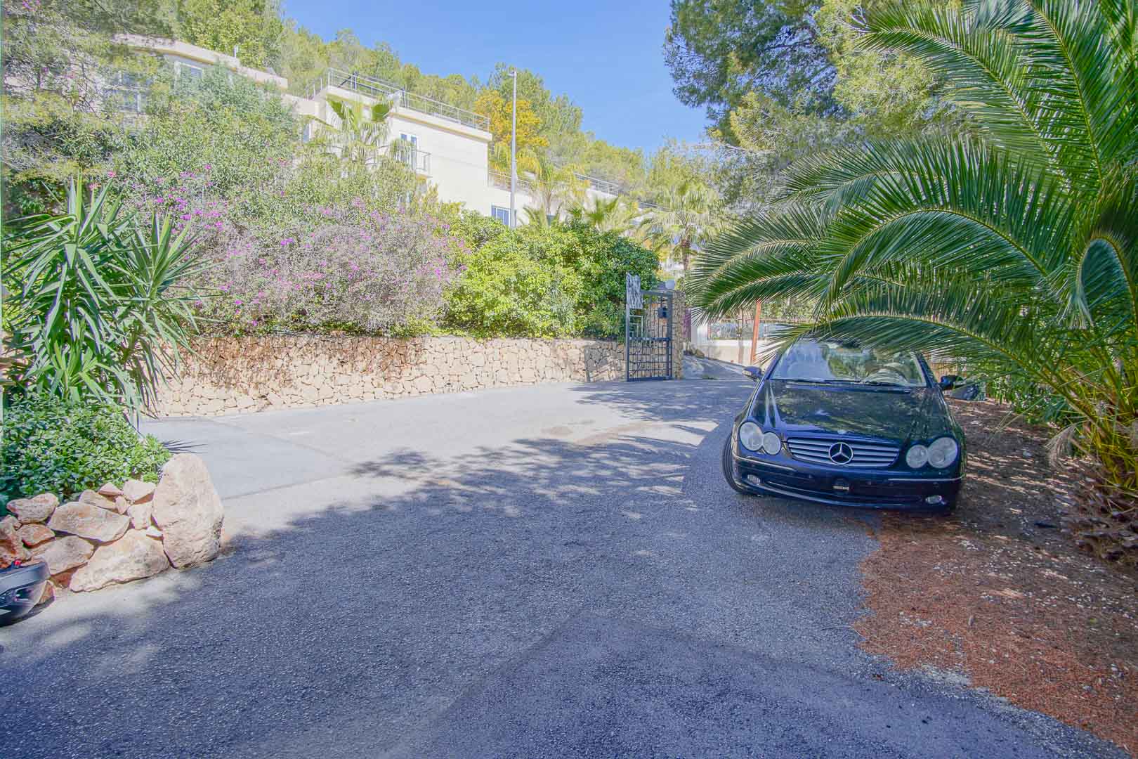 Großzügiger, gepflasterter Außenparkplatz, umgeben von Natursteinmauern und üppiger mediterraner Bepflanzung für maximale Privatsphäre.