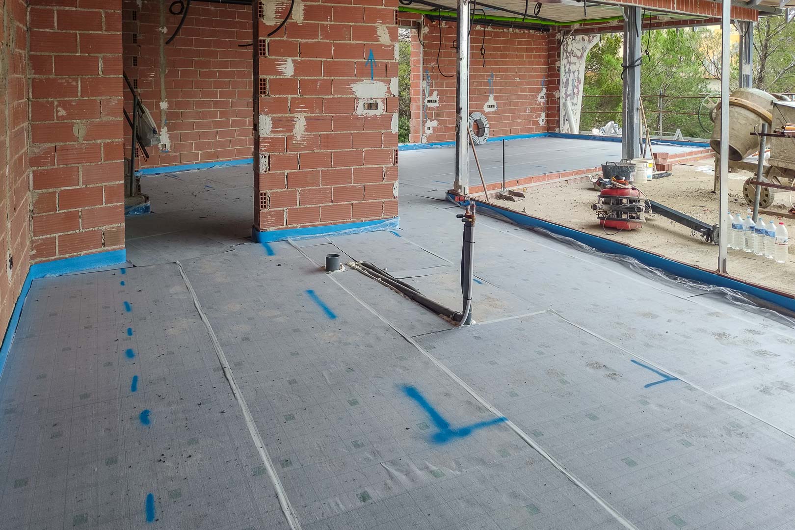 Baufortschritt mit Bodenisolierung und Rohrleitungsinstallationen als Vorbereitung für die Fußbodenheizung im Rohbau der Villa.