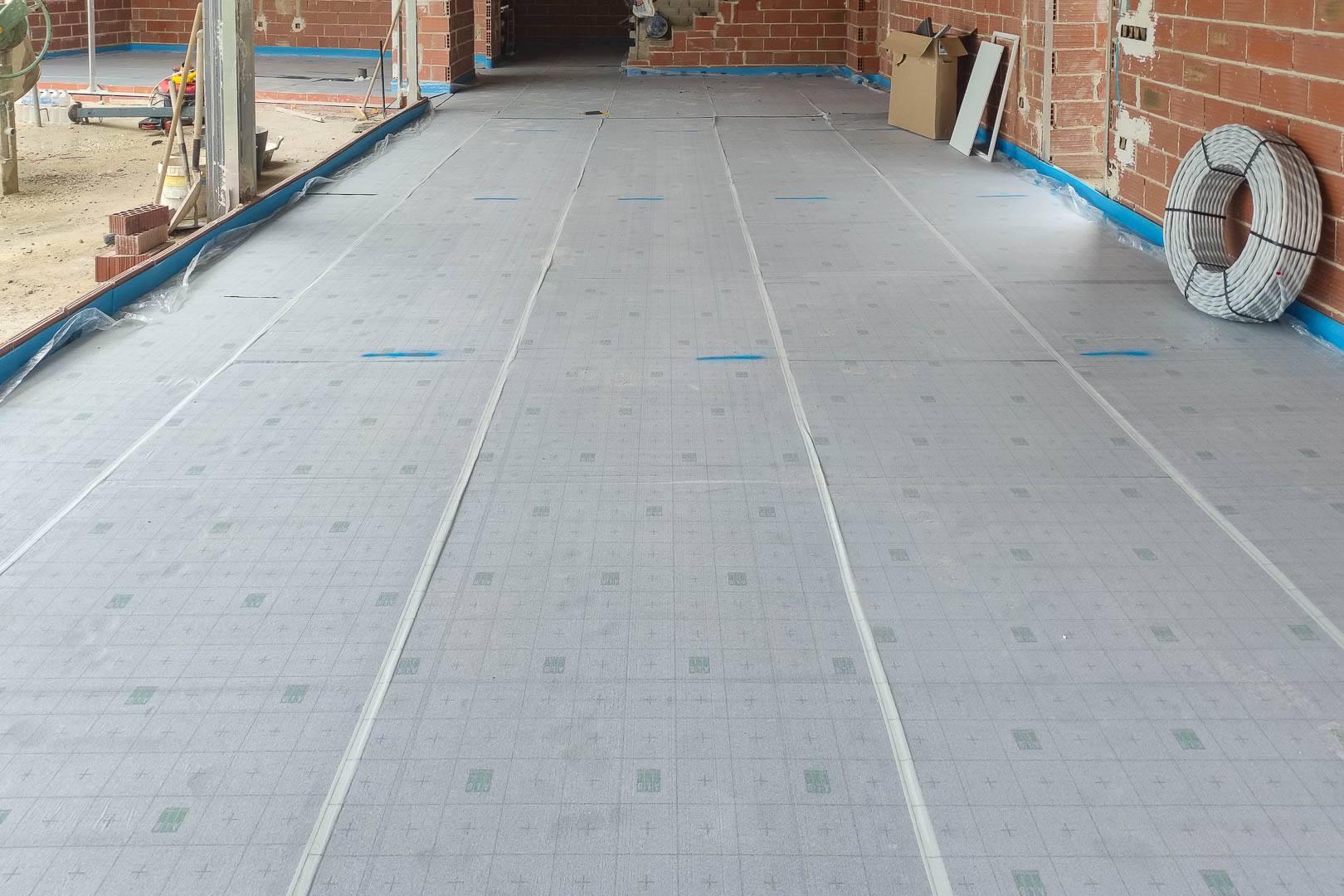 Installation von Wärmedämmplatten für die Fußbodenheizung, die die präzise technische Vorbereitung und hochwertigen Materialien im Innenraum zeigt.