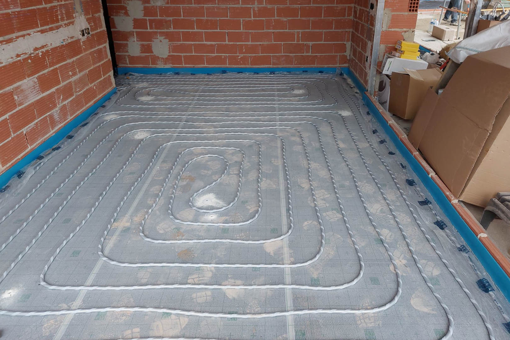 Installationsphase der Fußbodenheizung mit spiralförmig verlegten Rohren auf Dämmplatten und Randdämmstreifen im Rohbau.