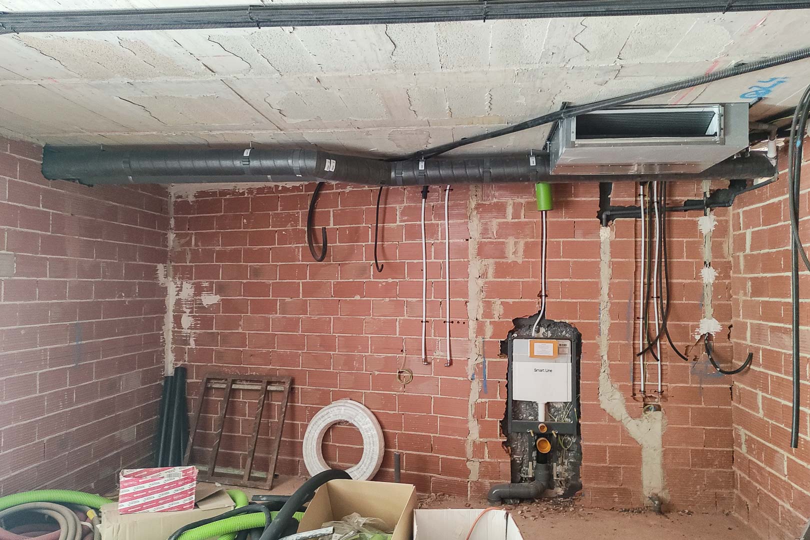 Rohbau-Detail mit installierter Luft-Wärmepumpen-Klimatisierung und Unterputz-Spülkasten für ein wandhängendes WC im Mauerwerk.
