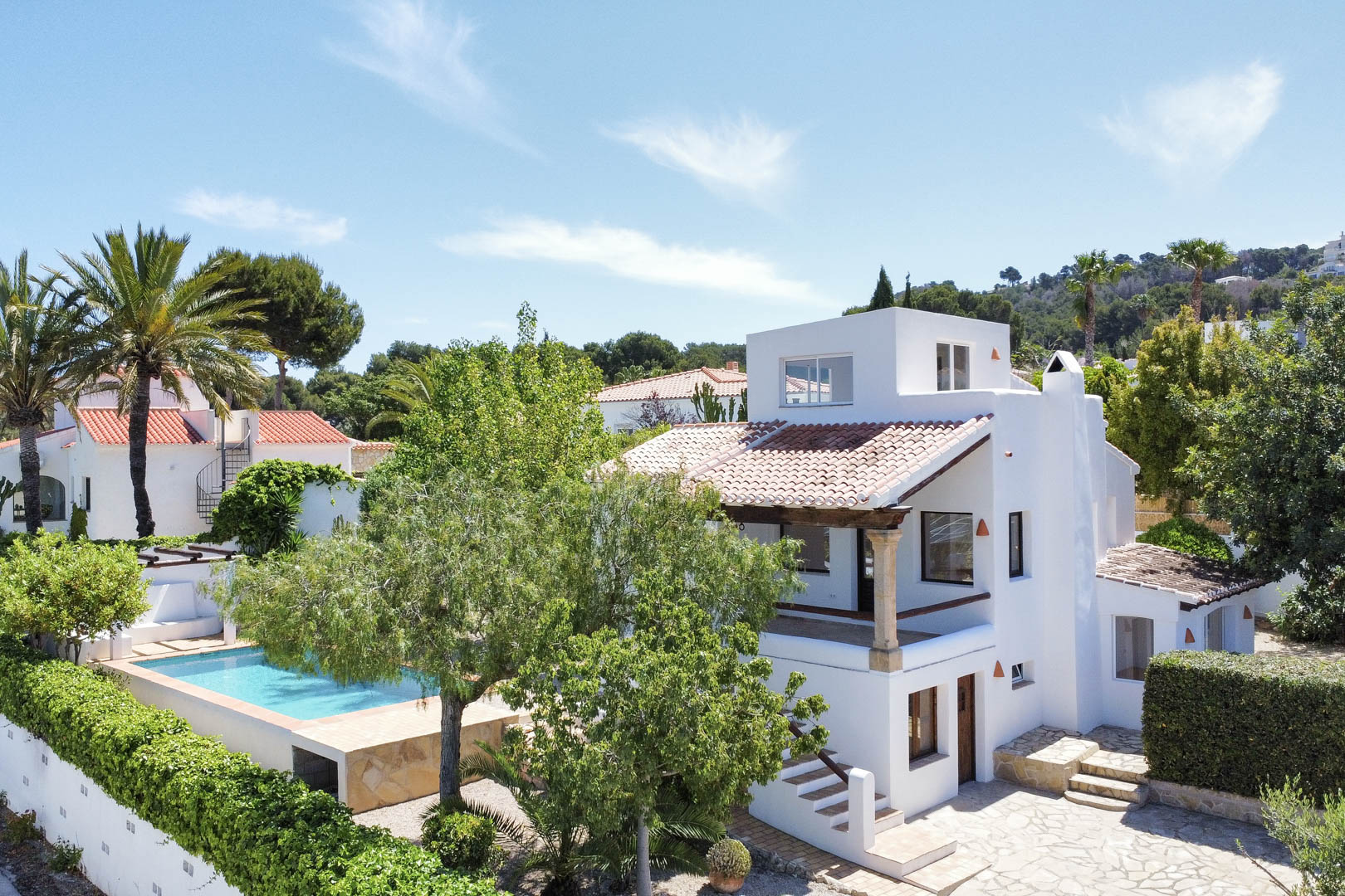 Erhöhte Ansicht der weißen Villa mit Pool, Garten und rotem Ziegeldach in Jávea.