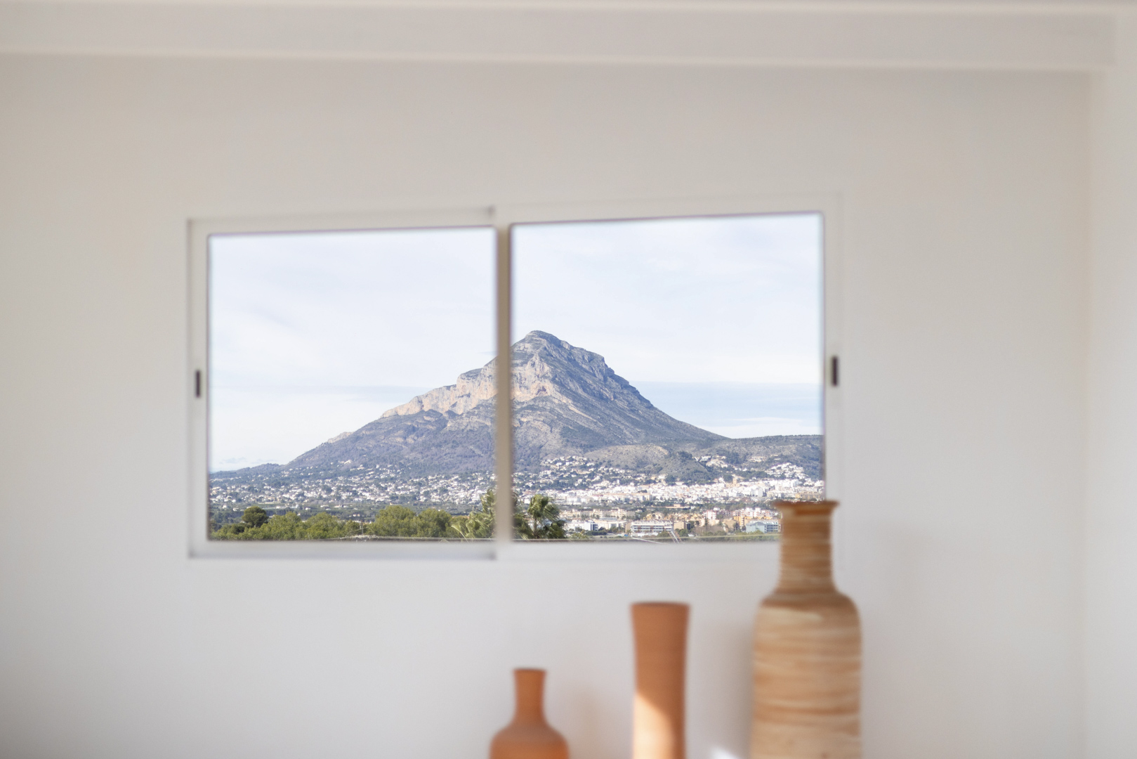 Innenansicht mit Keramikvasen und Fenster mit Bergblick.