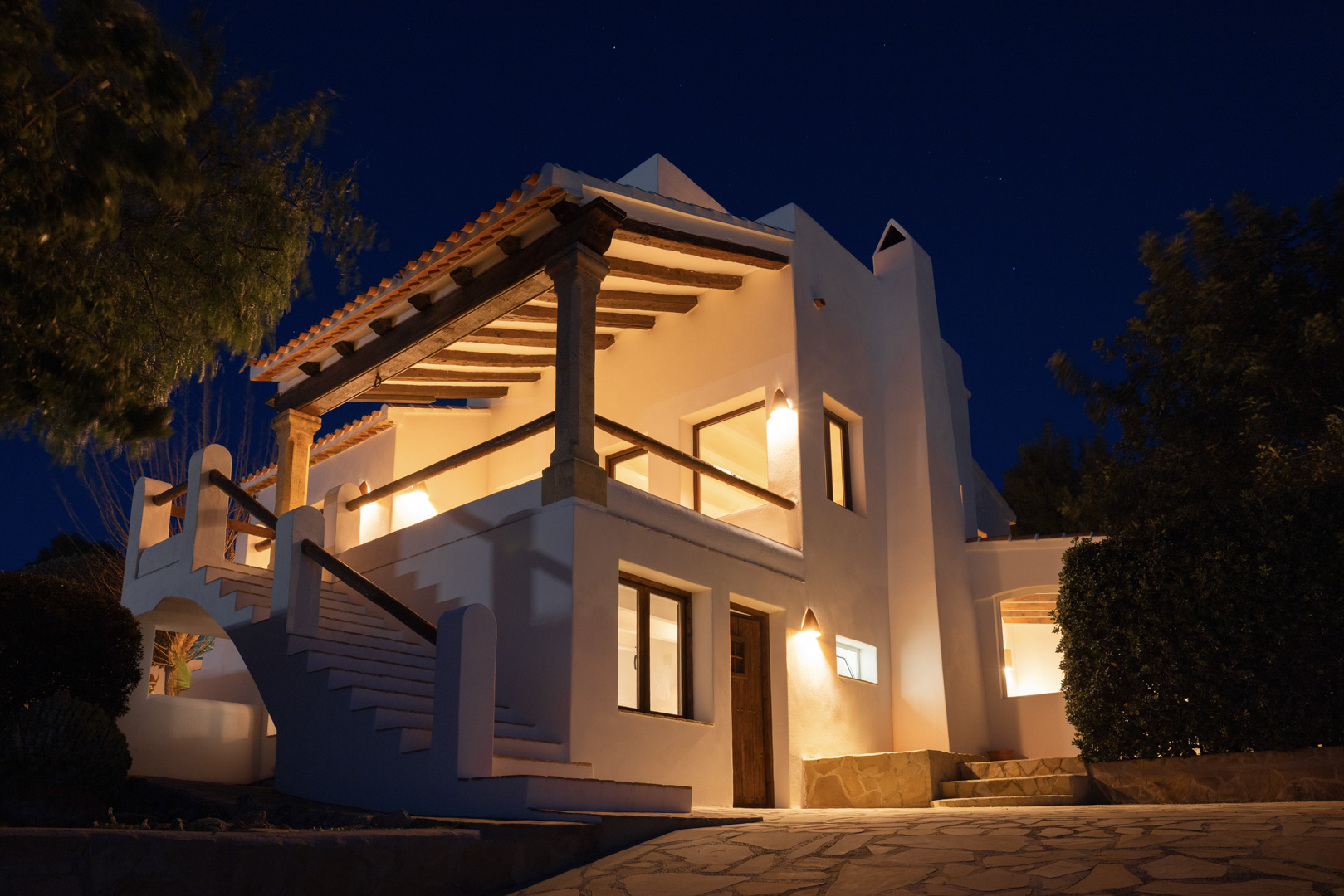 Nachtansicht der Villa in Tosalet, Jávea. Mediterrane Architektur mit überdachter Terrasse, warmer Beleuchtung und Steindetails.