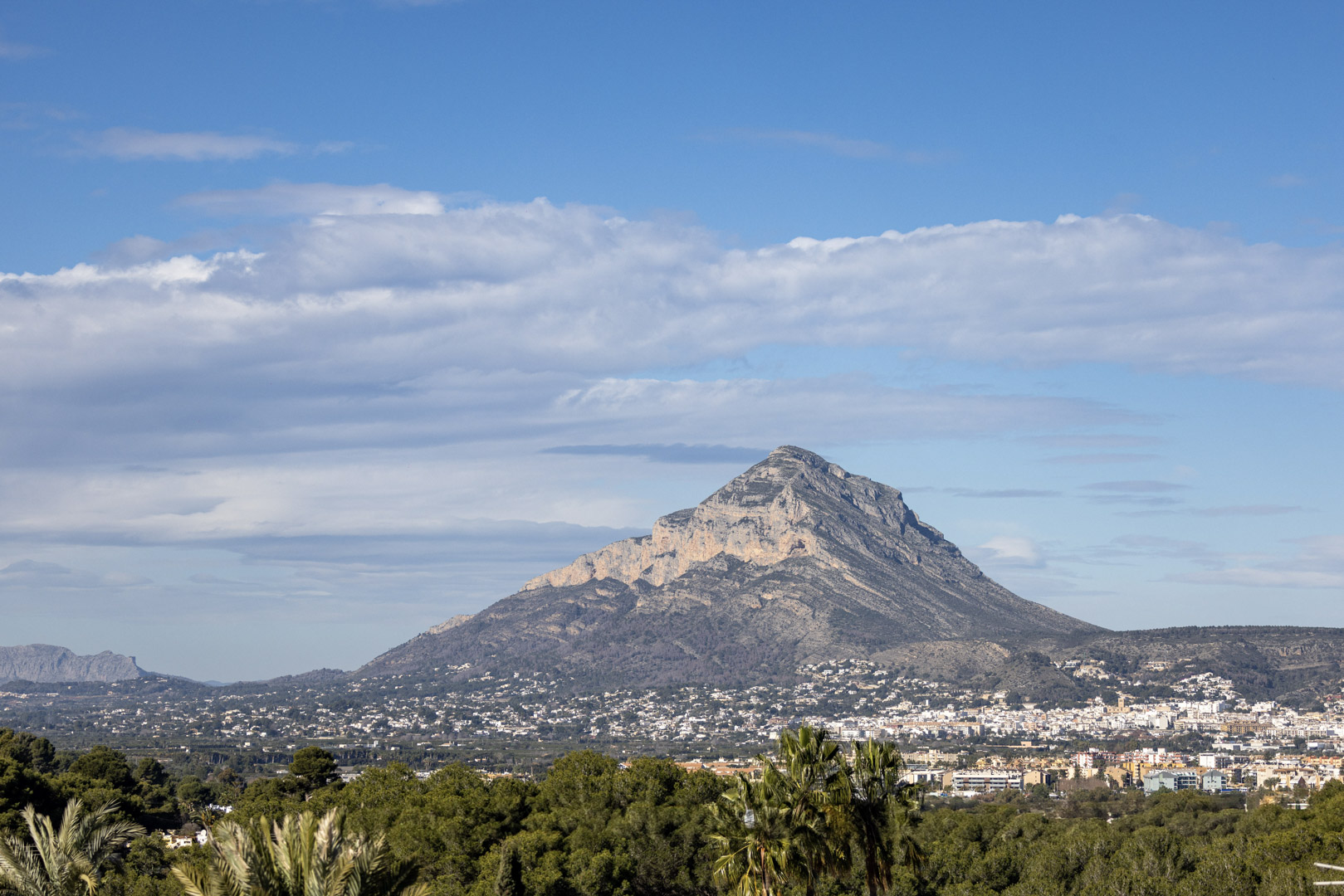Panoramablick auf den Montgó, Jávea, mit teilweise bewölktem Himmel und Vegetation im Vordergrund.